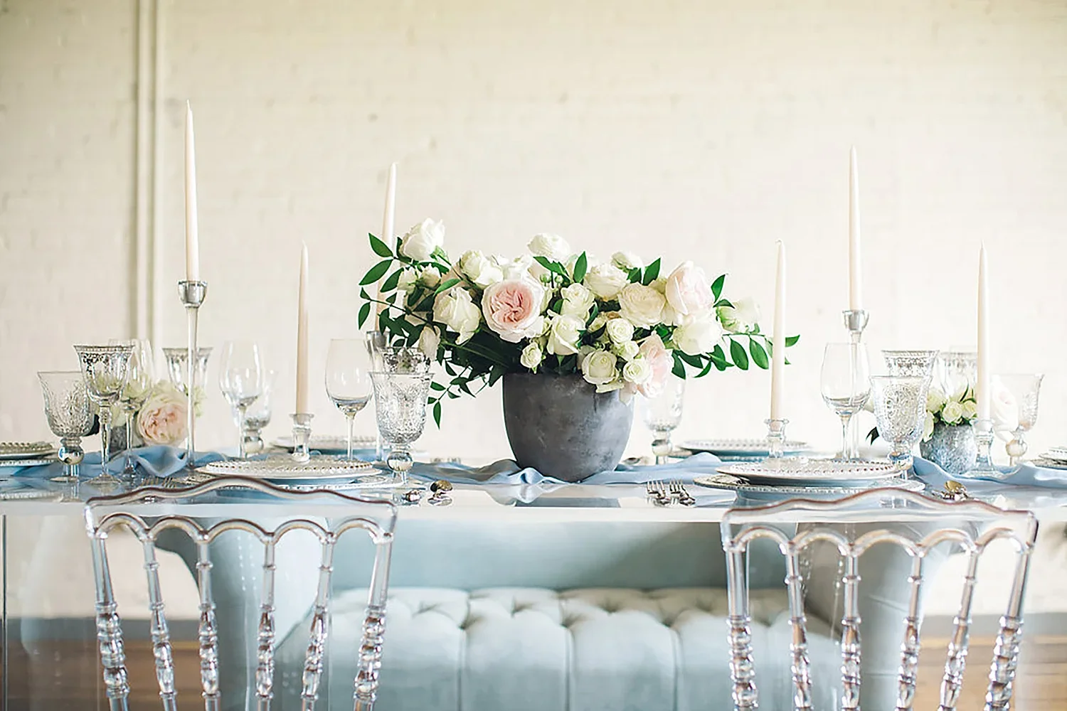 White flowers in a concrete vase on a acrylic table with ghost chairs
