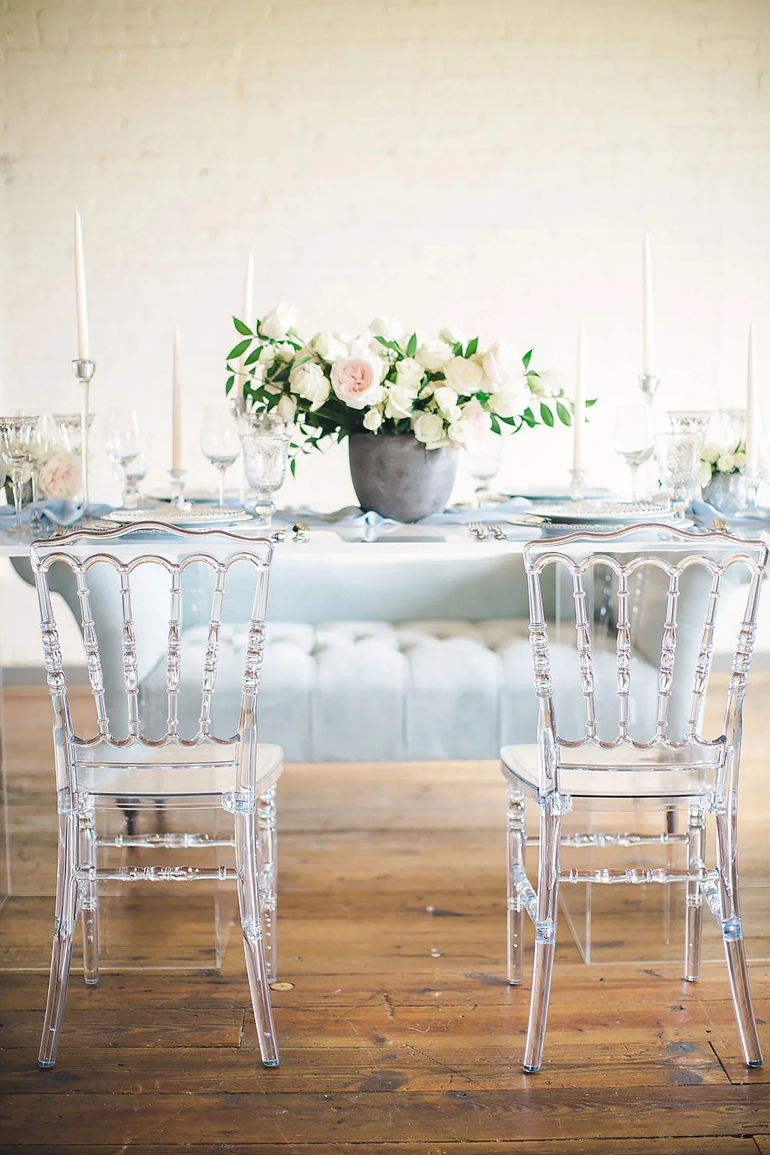 A acrylic table with a dusty blue china charger and tapered candles at Brik Venue