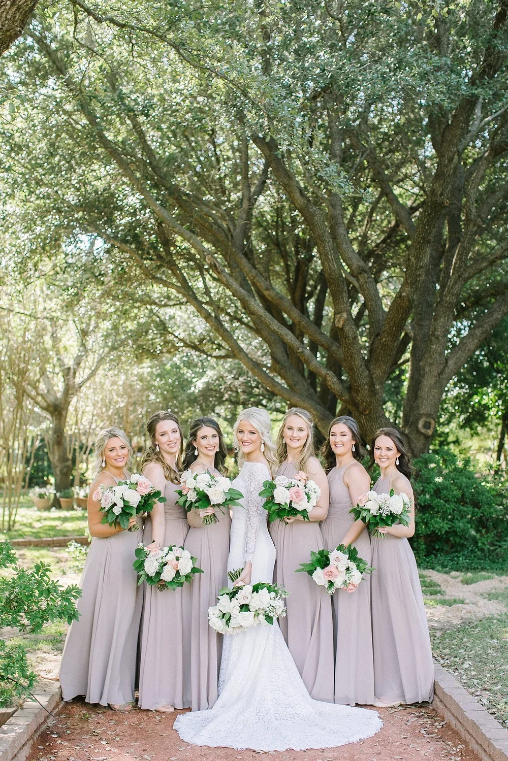 Bride and her bridesmaids in taupe dresses with white bouquets