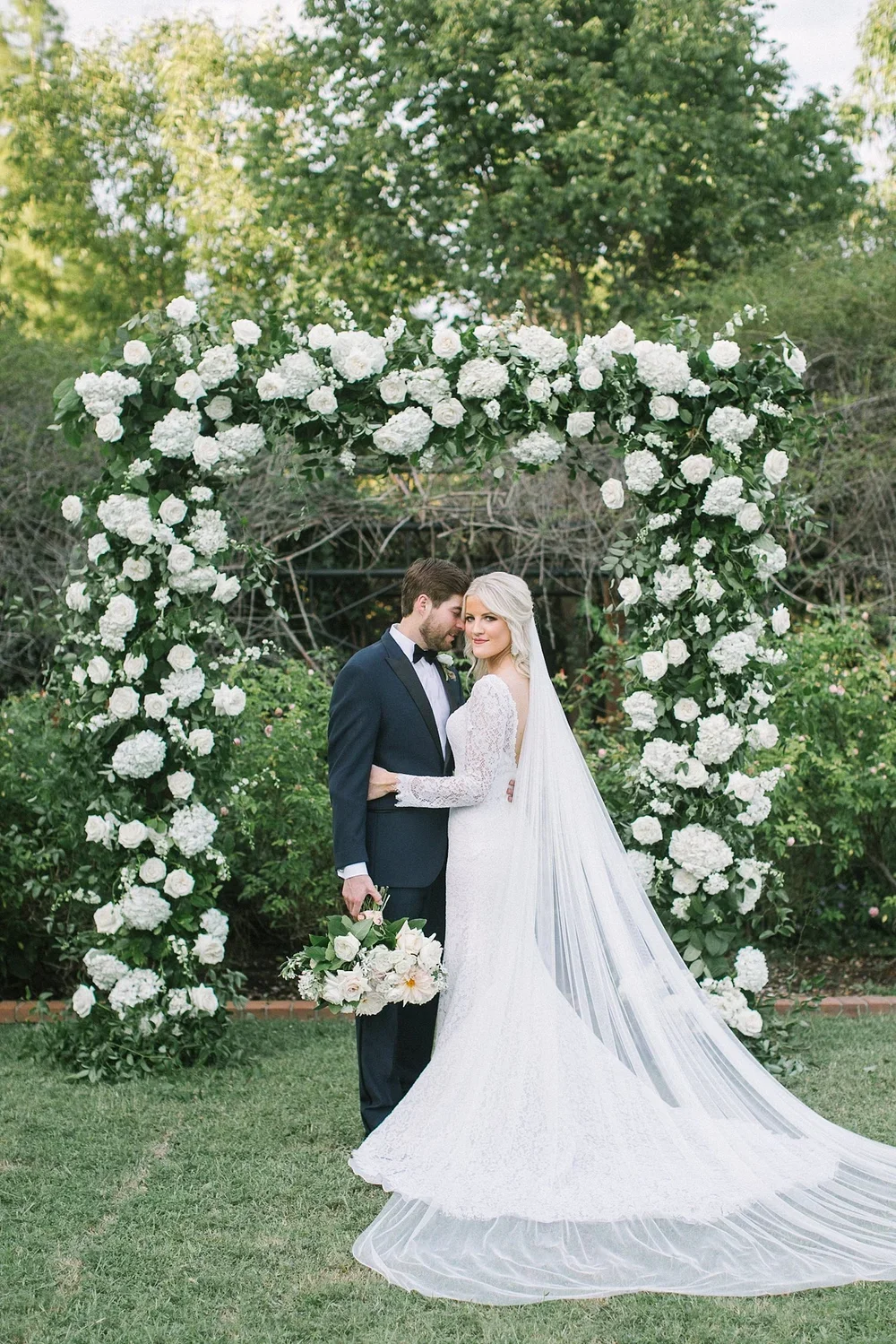 Bride and groom in front of white organic archway at clark gardens wedding