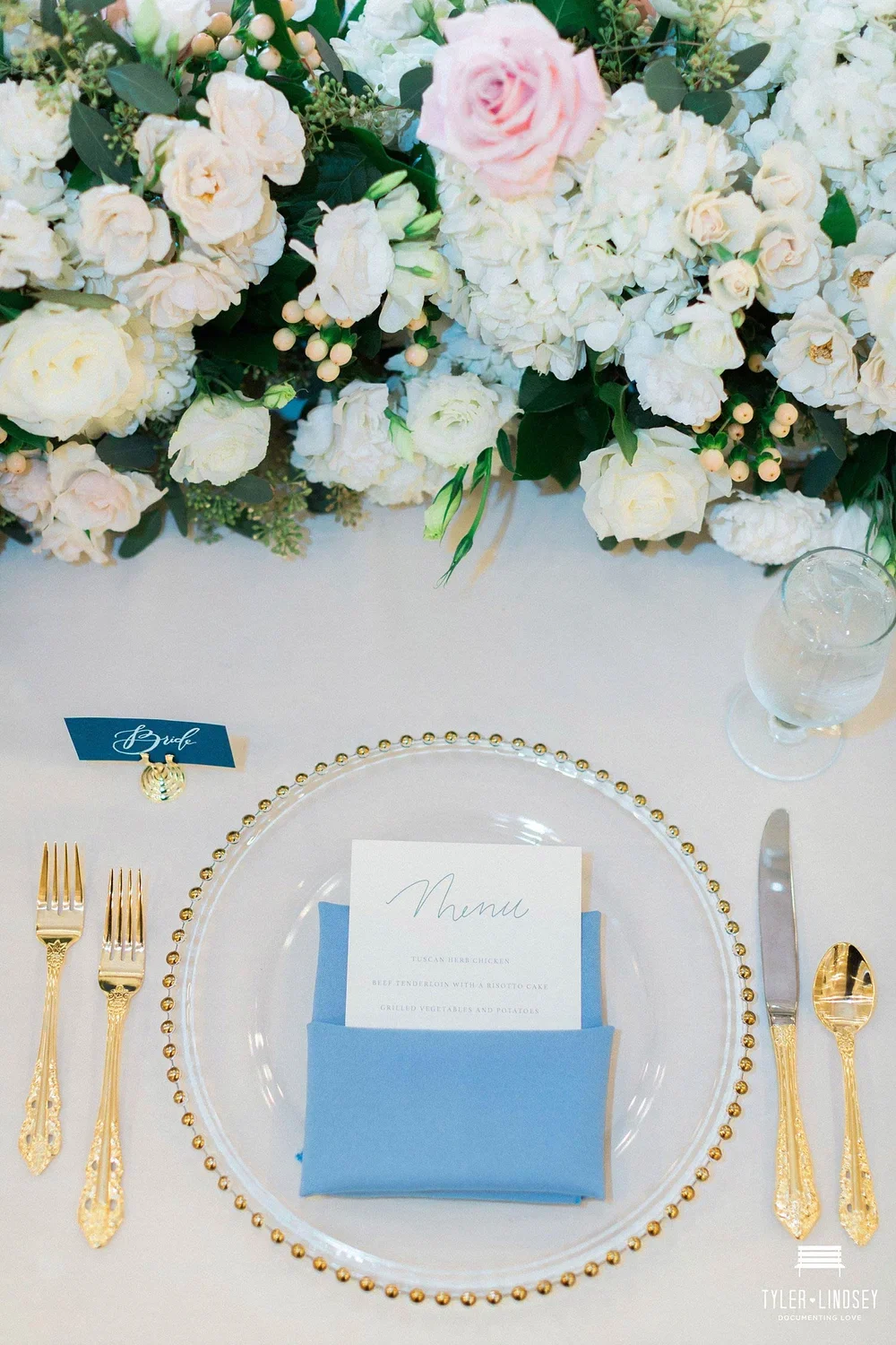 Dallas ballroom wedding with a gold beaded charger and blue escort card