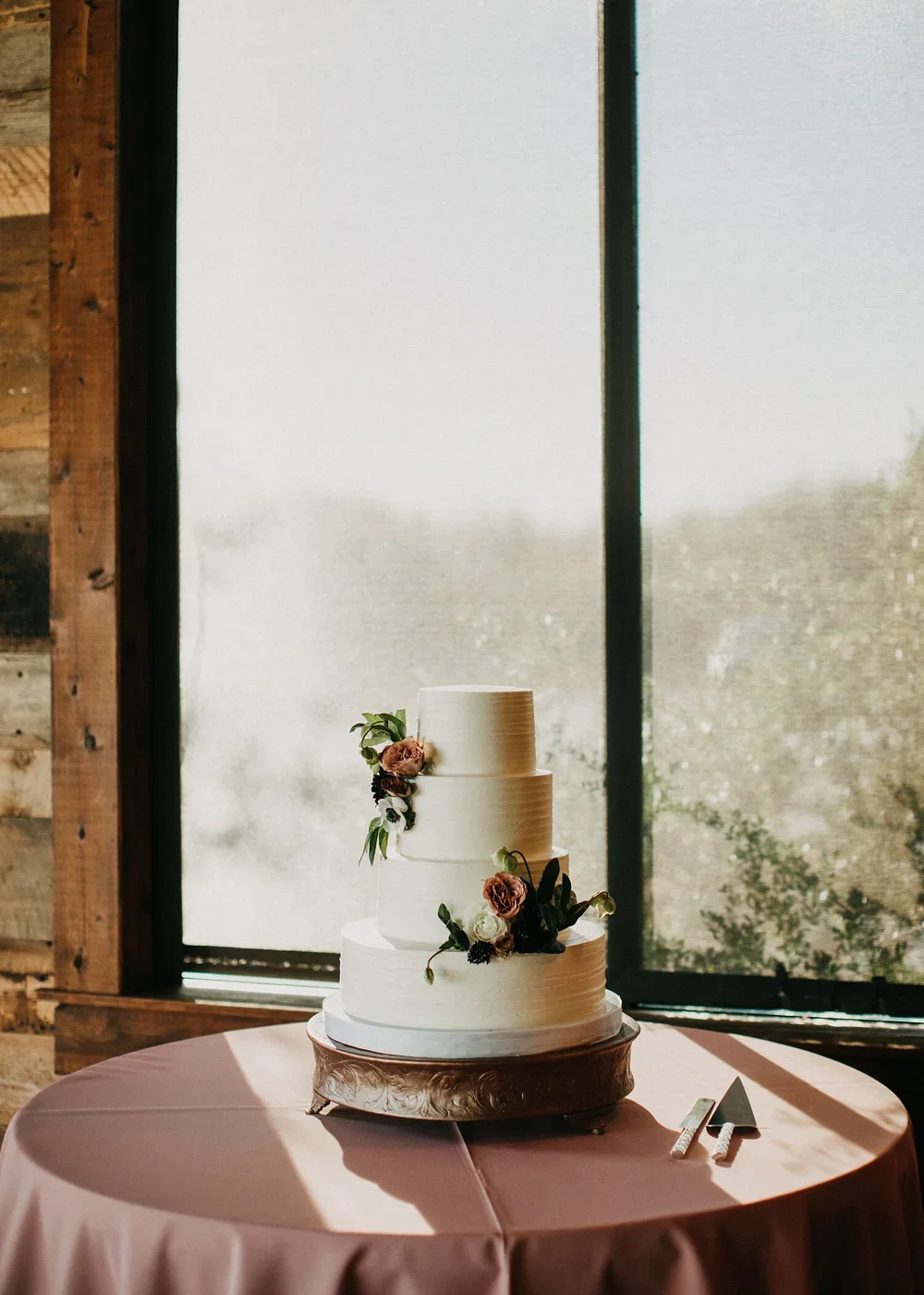 Three tier wedding cake with pink flowers on a mauve linen