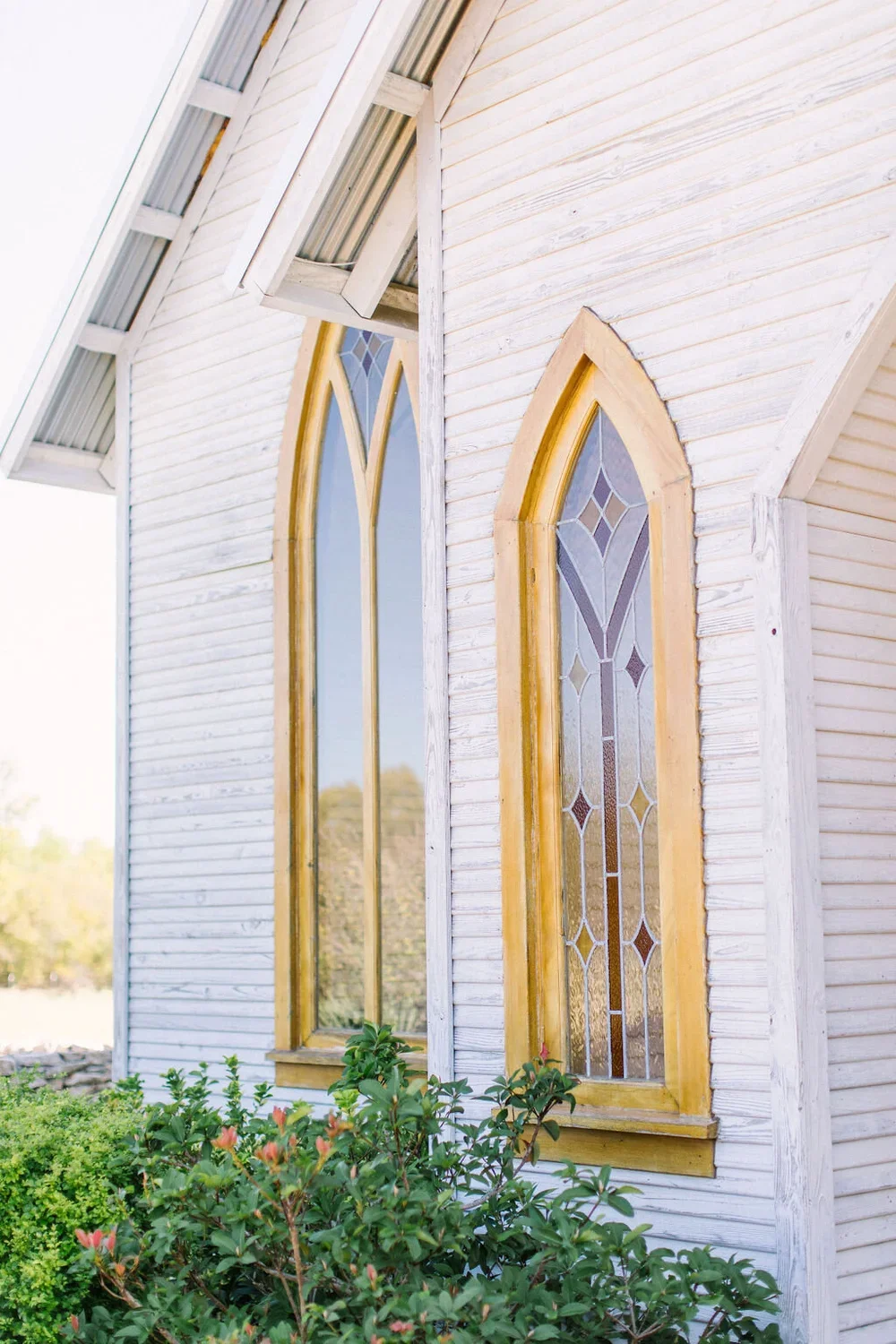 Stain glass windows on a white chapel with a wood frame