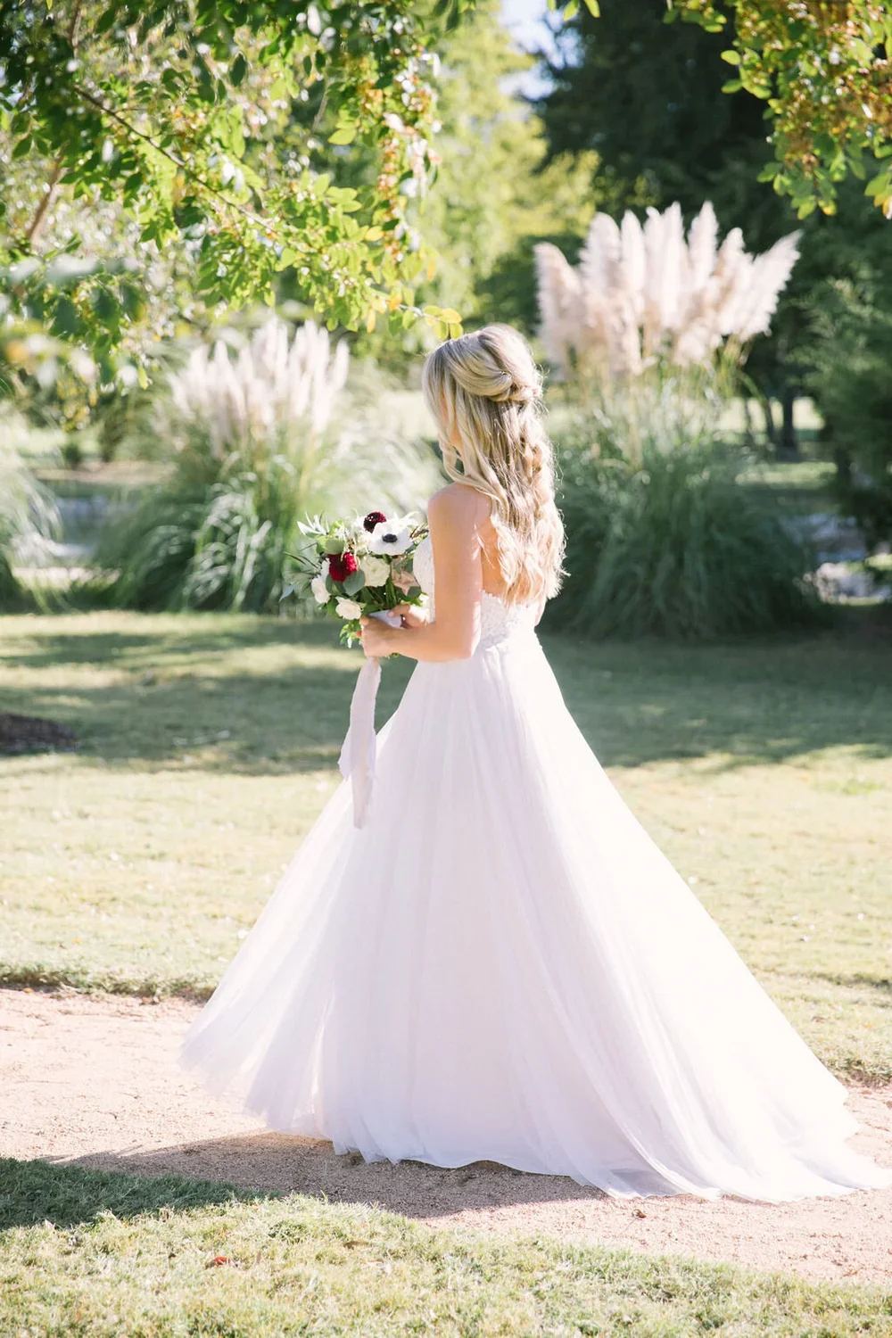 Boho bride walking green field at Texas wedding