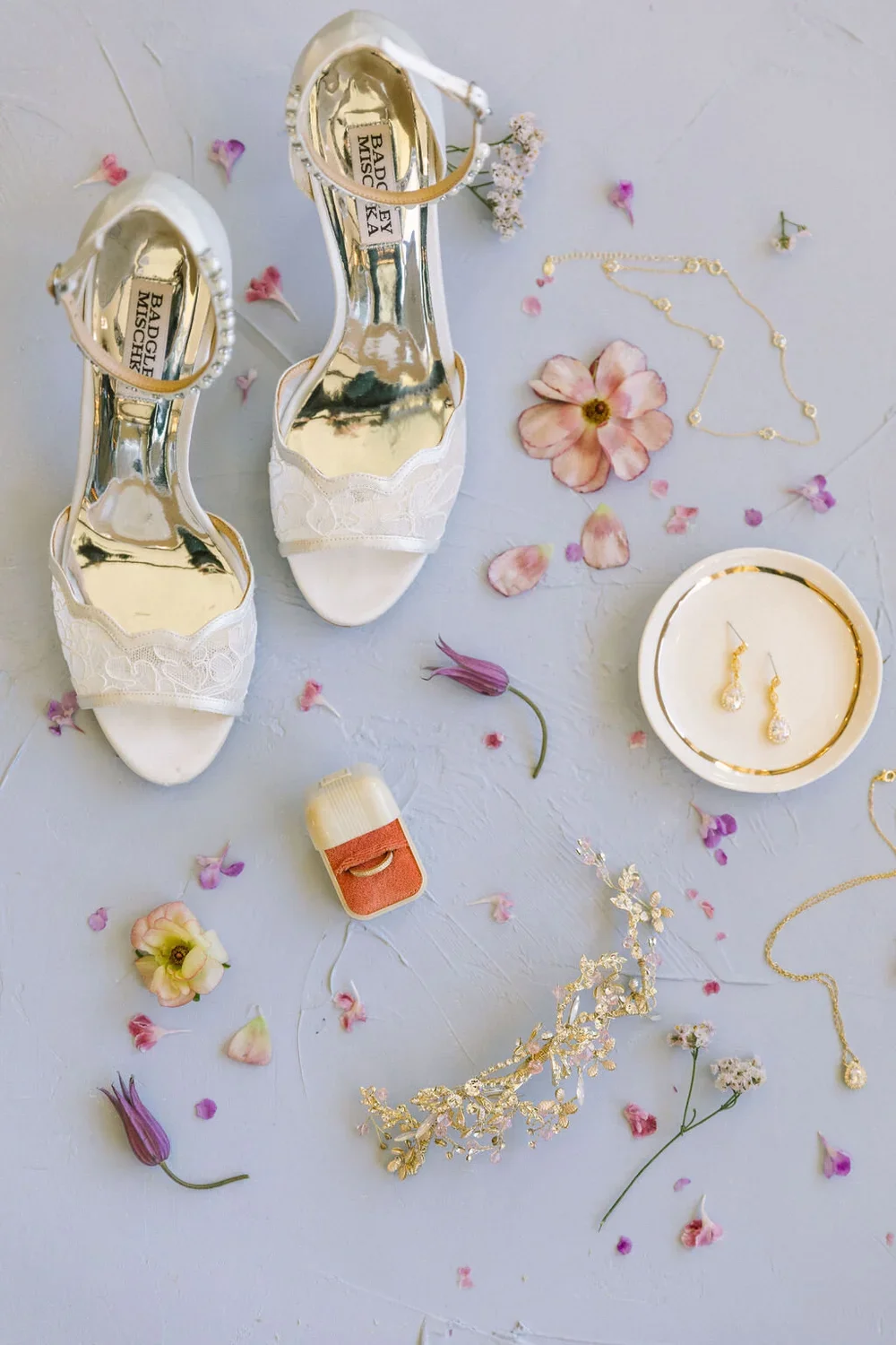 Bridal detail flat lay with a orange ring box and white shoes on a purple backdrop