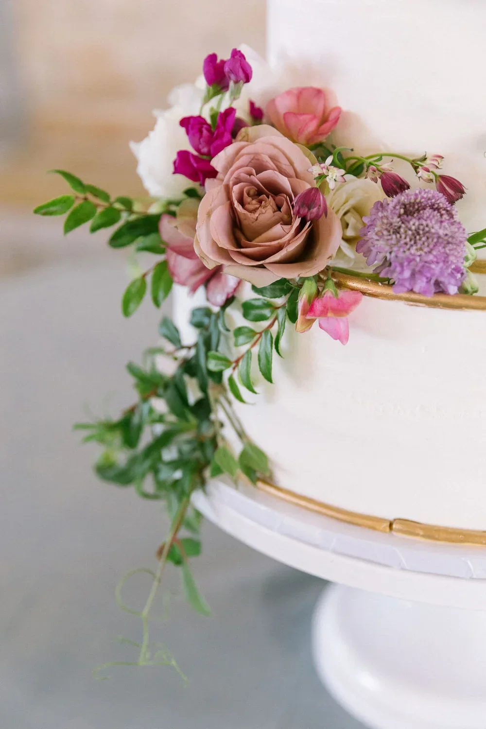 White cake with a copper rim and pink and purple flowers