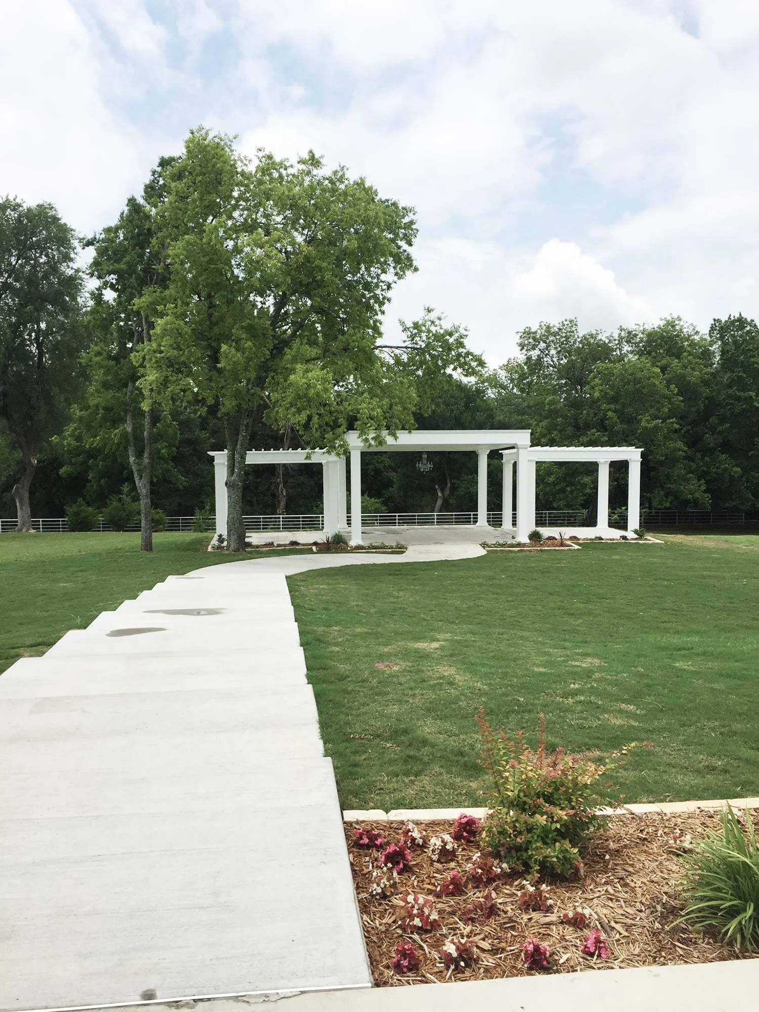 Firefly Gardens ceremony area three white trellis with concrete pathway