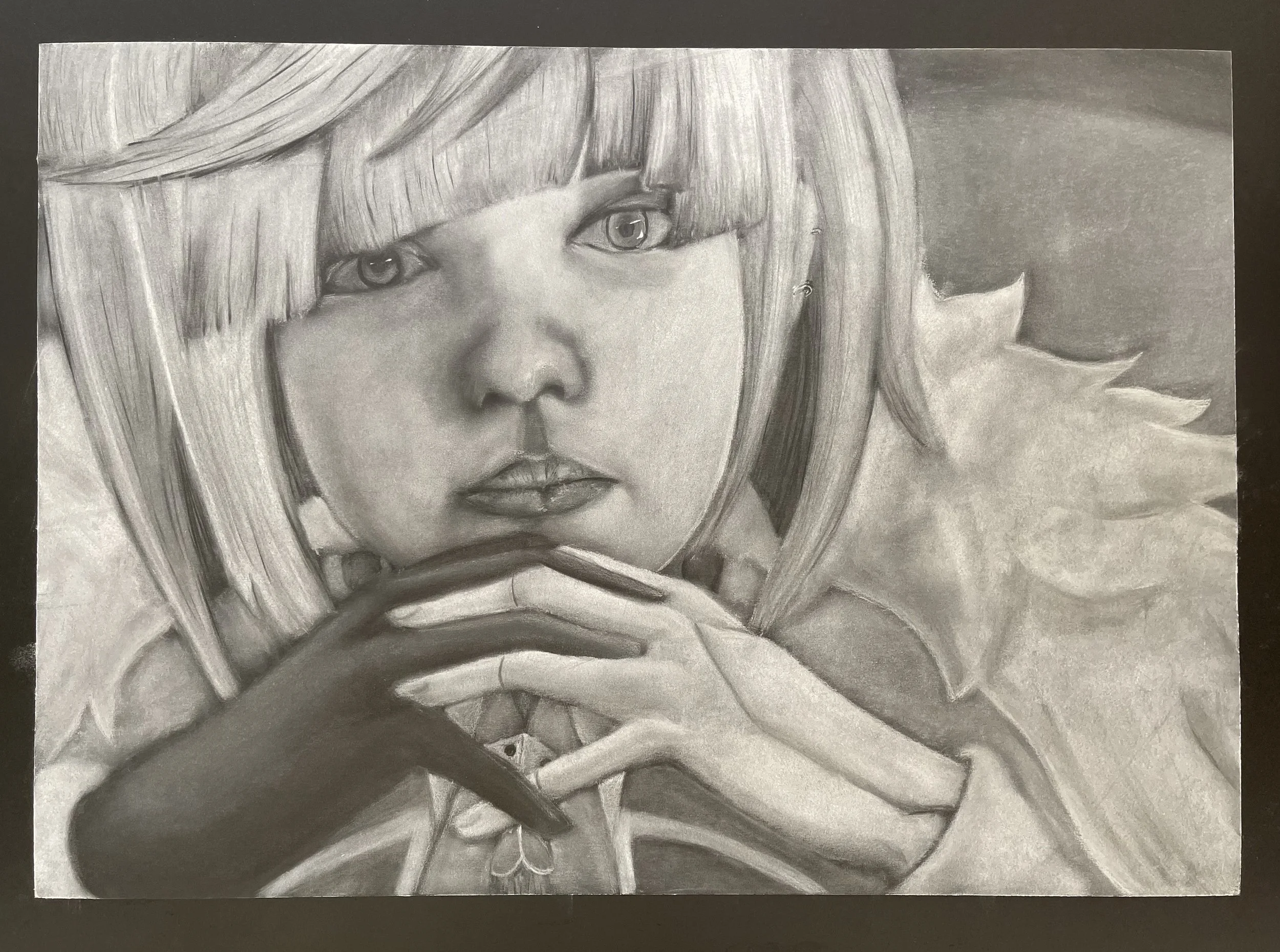 A detailed pencil drawing of a young girl with shoulder-length hair and bangs, staring intently with her hands clasped near her lips, and a necklace with a leaf-shaped pendant around her neck.