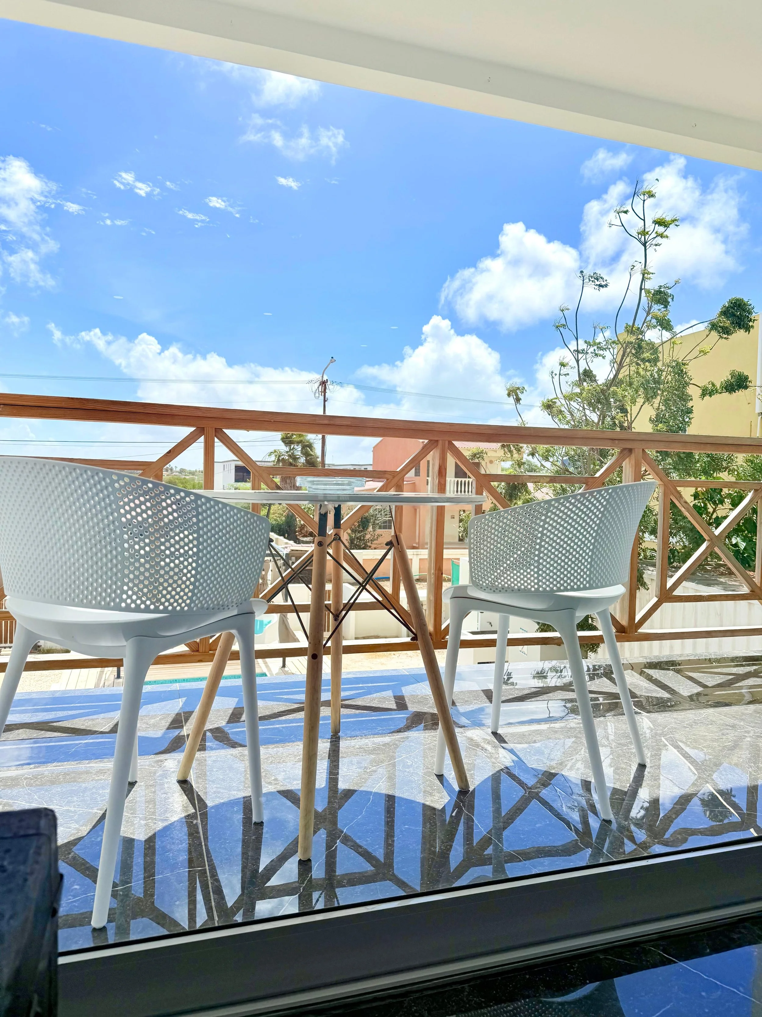Stylish outdoor dining corner with modern white chairs and a view toward the terrace.