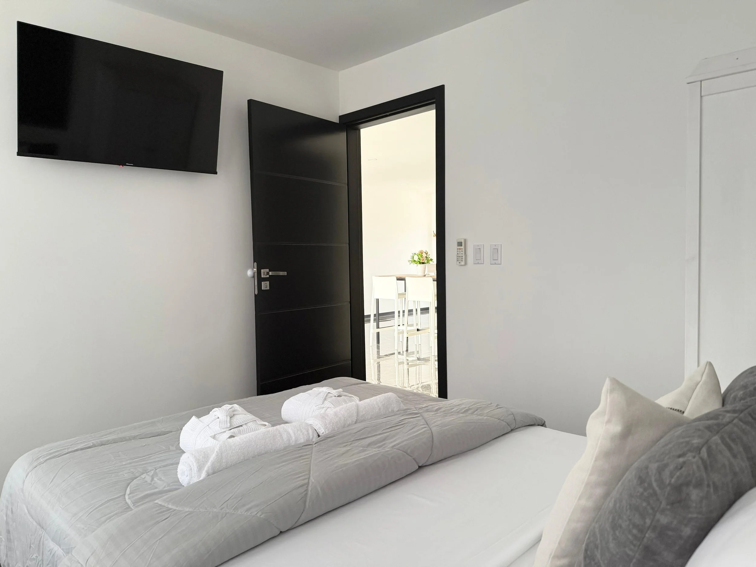 Modern guest room with full-size bed and wall-mounted TV at Kas Pitava.