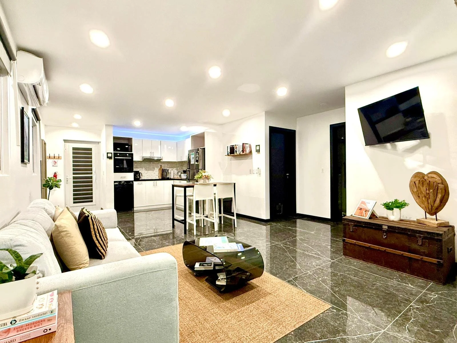 Living room at Kas Pitava with modern decor, bookshelf, and cozy white couch.