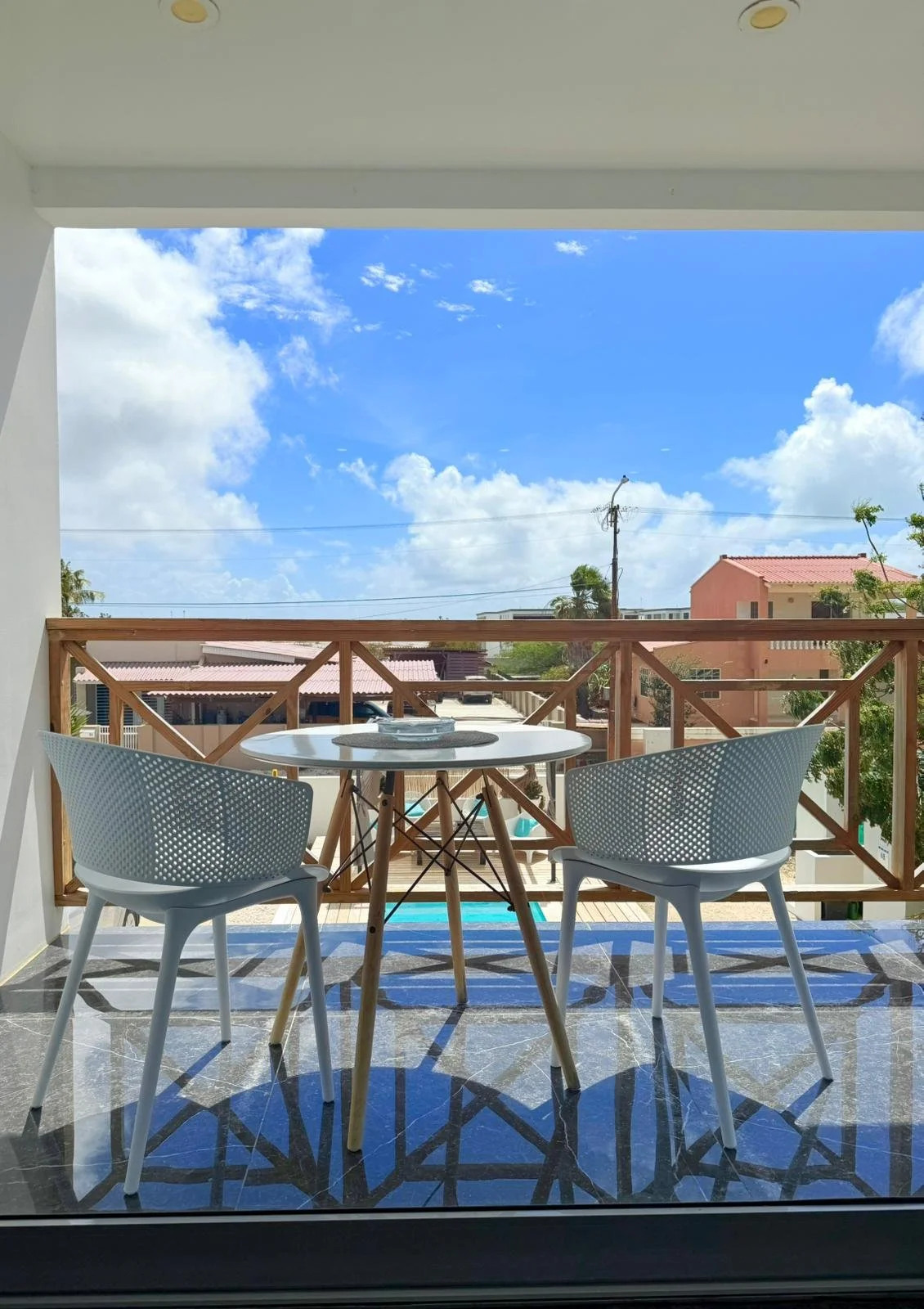 Stylish outdoor dining corner with modern white chairs and a view toward the terrace.