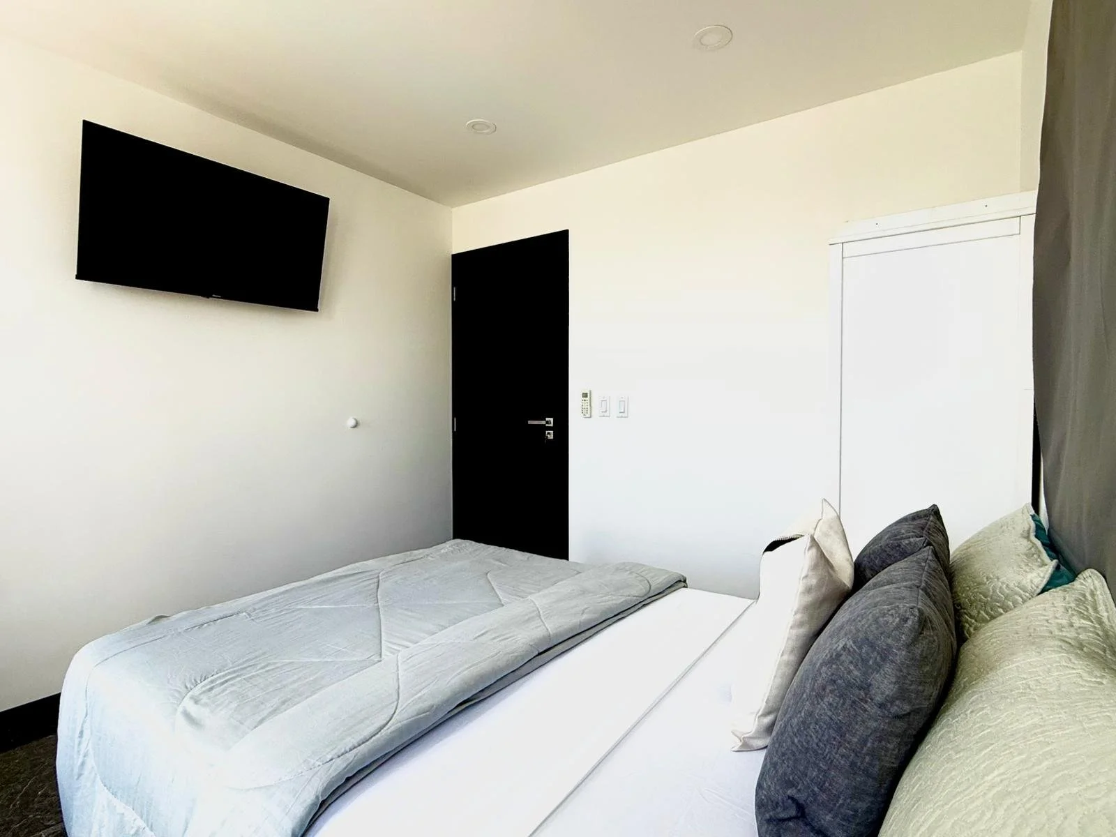 Modern guest room with full-size bed and wall-mounted TV at Kas Pitava.