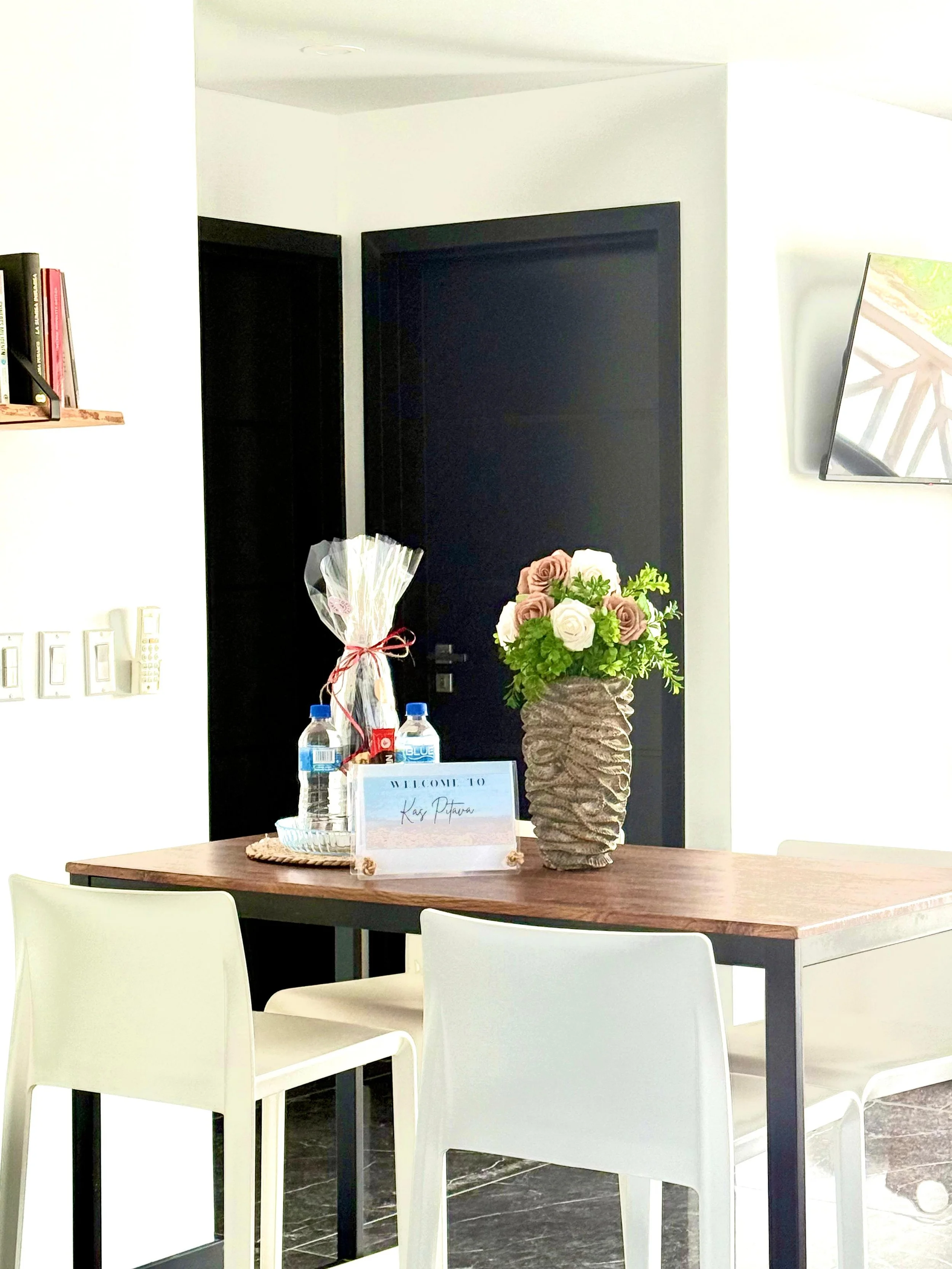 Fresh flowers and welcome amenities on the wooden dining table at Kas Pitava.