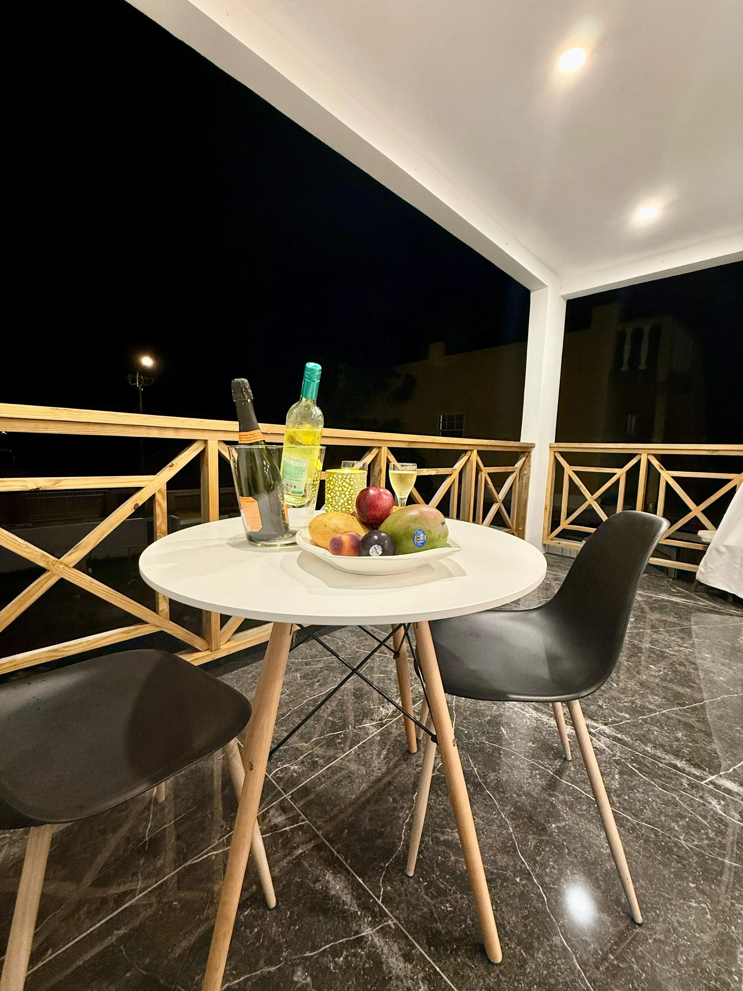 Romantic dinner setup with wine and candles on the private rooftop terrace at night.