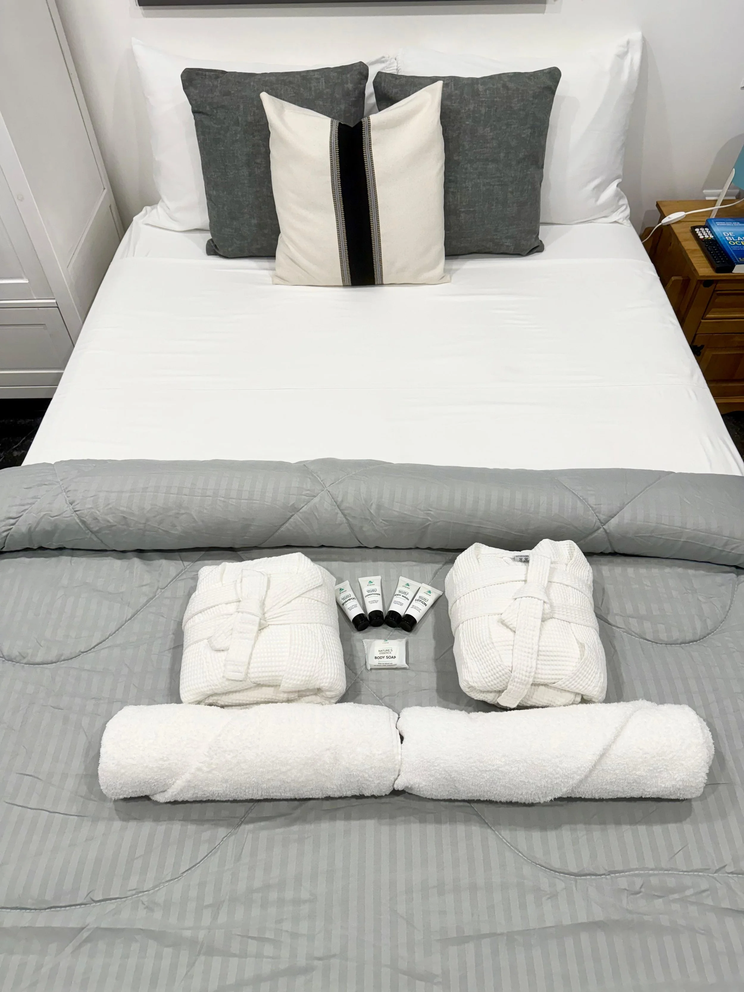Bed with white and grey textiles, perfect for a relaxing retreat – Kas Pitava Bonaire.