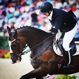 A person in equestrian attire riding a horse during a competition.