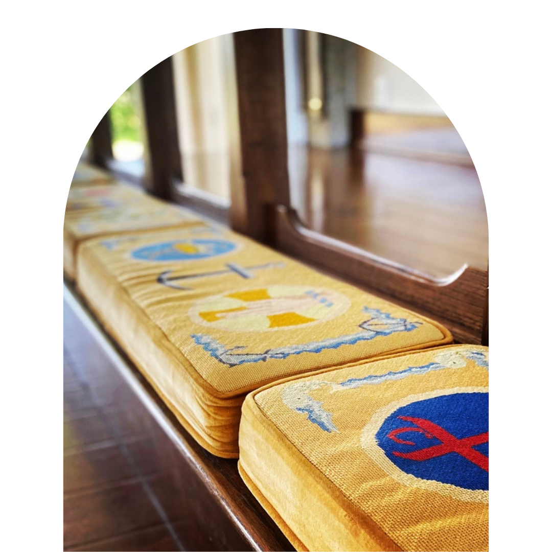 Stack of yellow cloth with nautical and maritime-themed embroidery placed on a wooden surface next to a mirror.