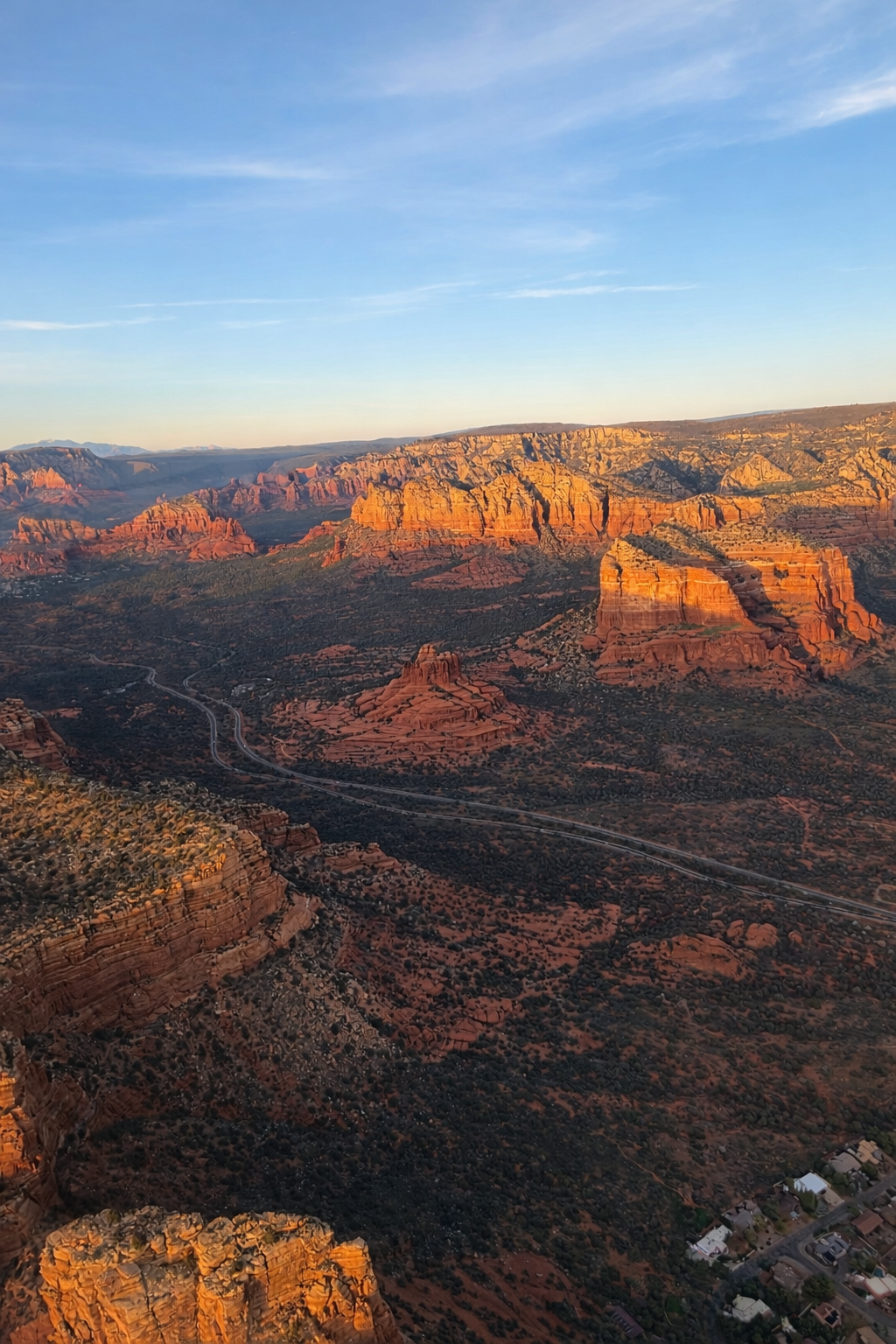 Aerial photo of golden hour sunset shining on the red rocks of Sedona - Bluebird Air Tours