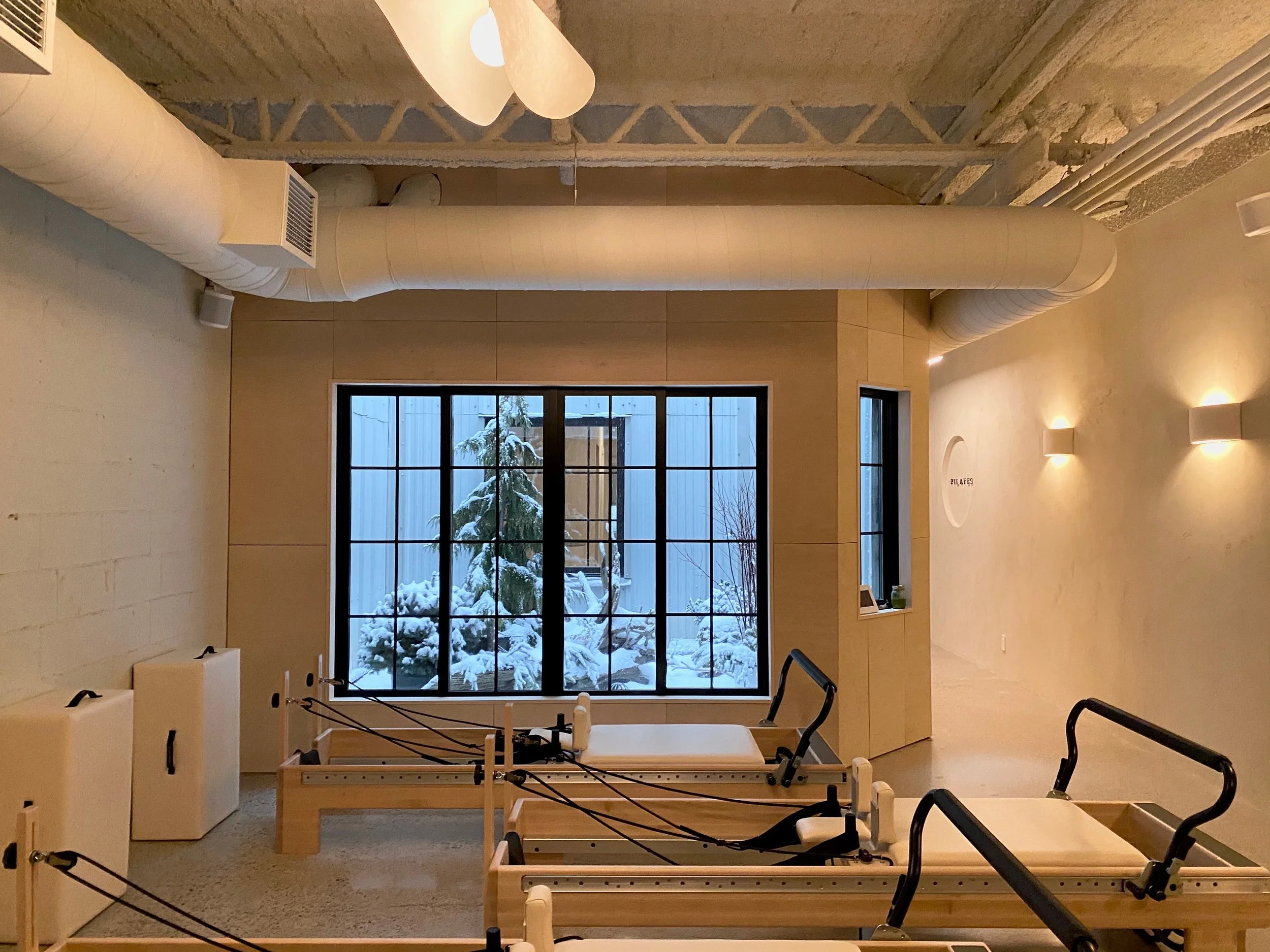 A physical therapy or rehabilitation room with two therapy beds and a window showing snow-covered trees outside.