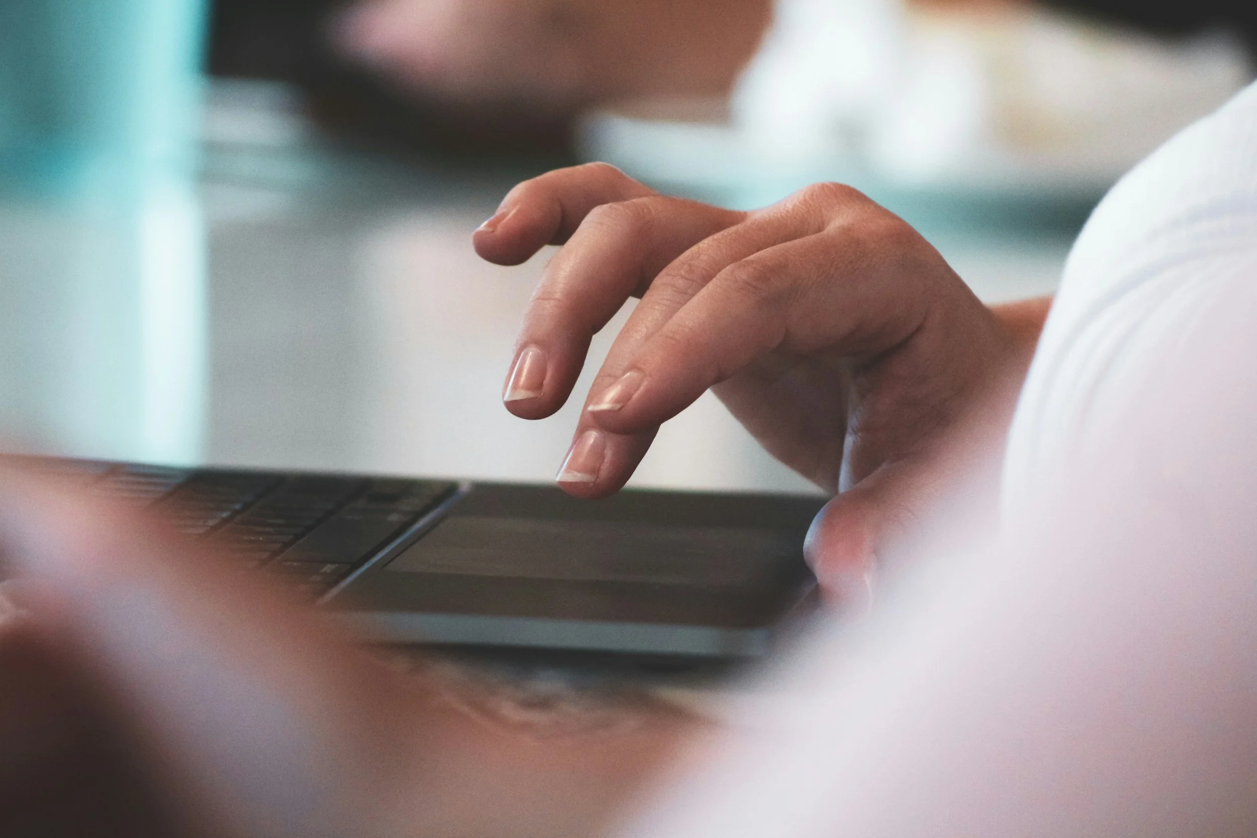 Close-up of a person's hand typing on a laptop keyboard.
