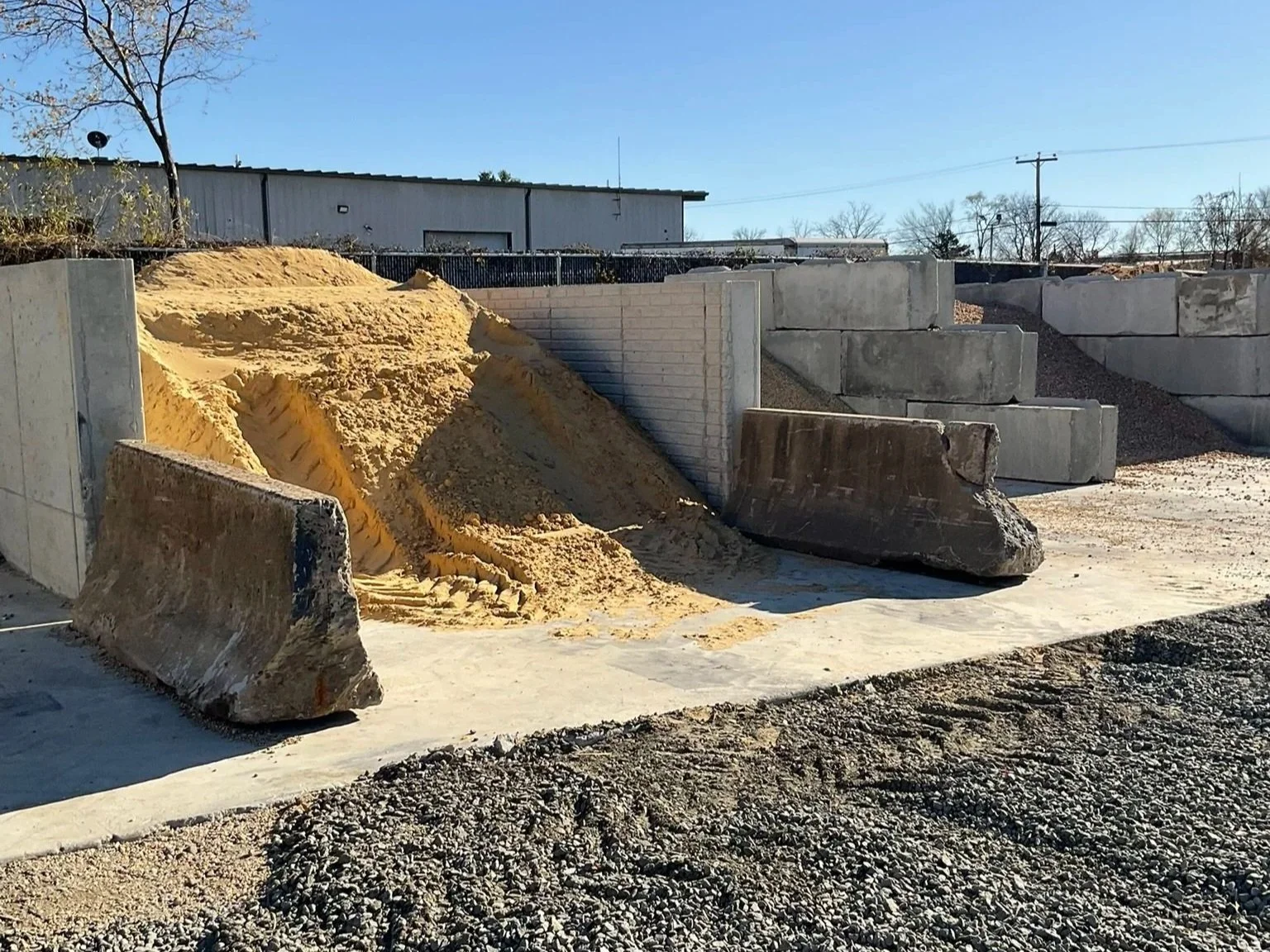 Photo of sand bin with additional bin in background containing crushed bluestone of various sizes.