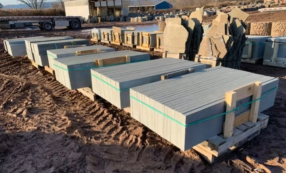 Pallets of bluestone treads, laid out in a row in front of various other flagstone products.