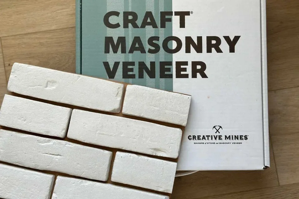 Box of craft masonry veneer with white brick samples in front.