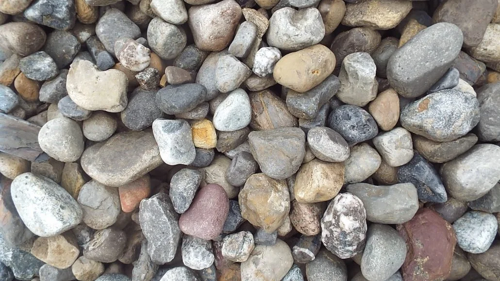 Multi-colored, naturally tumbled river gravel containing reds, blues, buffs and grays.  Commonly known as River Jack or Chalet Stone.