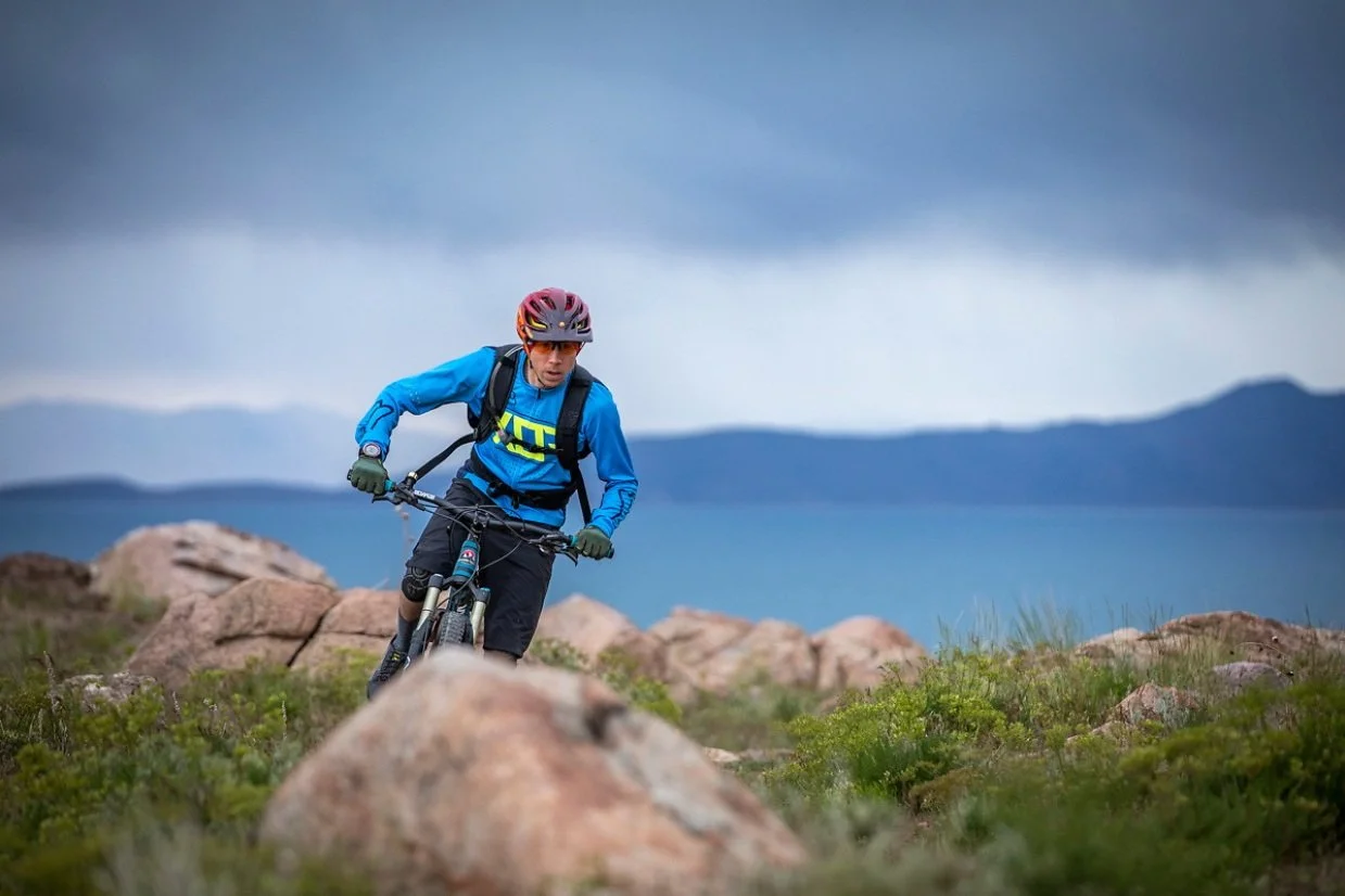 Mountain biker riding rocky singletrack on Antelope Island with lake and mountains in the background
