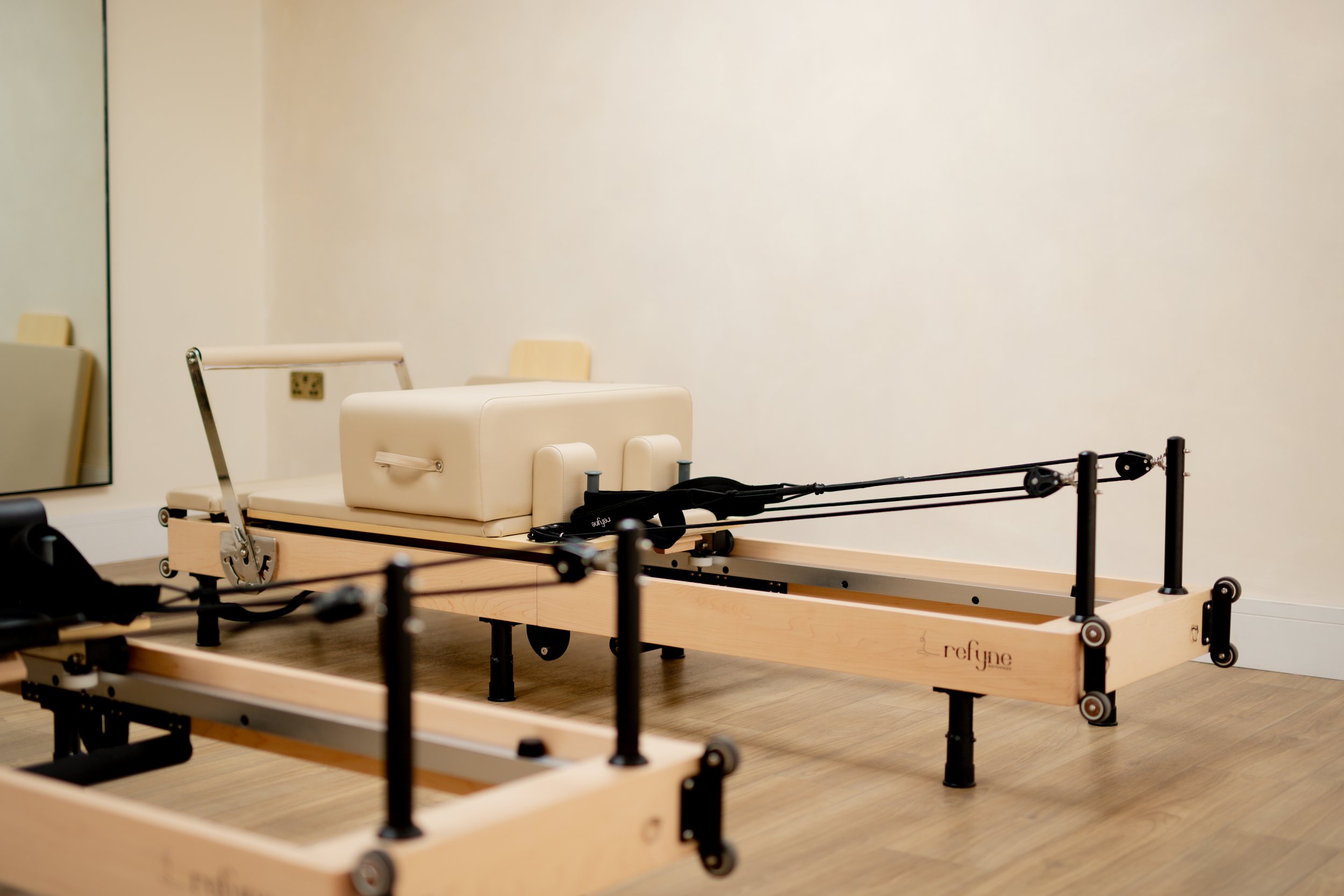 A ReFyne Pilates reformer machine in a room with light-colored walls and wood flooring