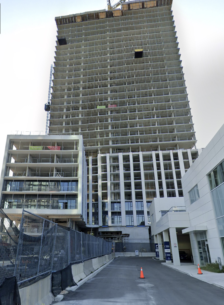 Under construction high-rise building with scaffolding and construction barriers at street level.