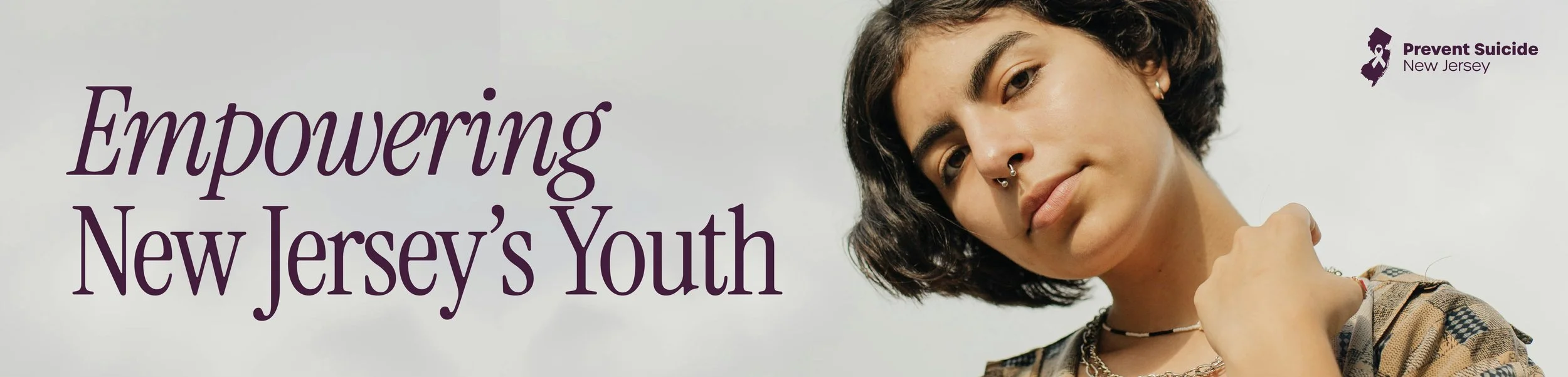 A young person with dark, curly hair, multiple facial piercings, and jewelry, looking at the camera, with text that says 'Empowering New Jersey's Youth' and a logo for Prevent Suicide New Jersey.