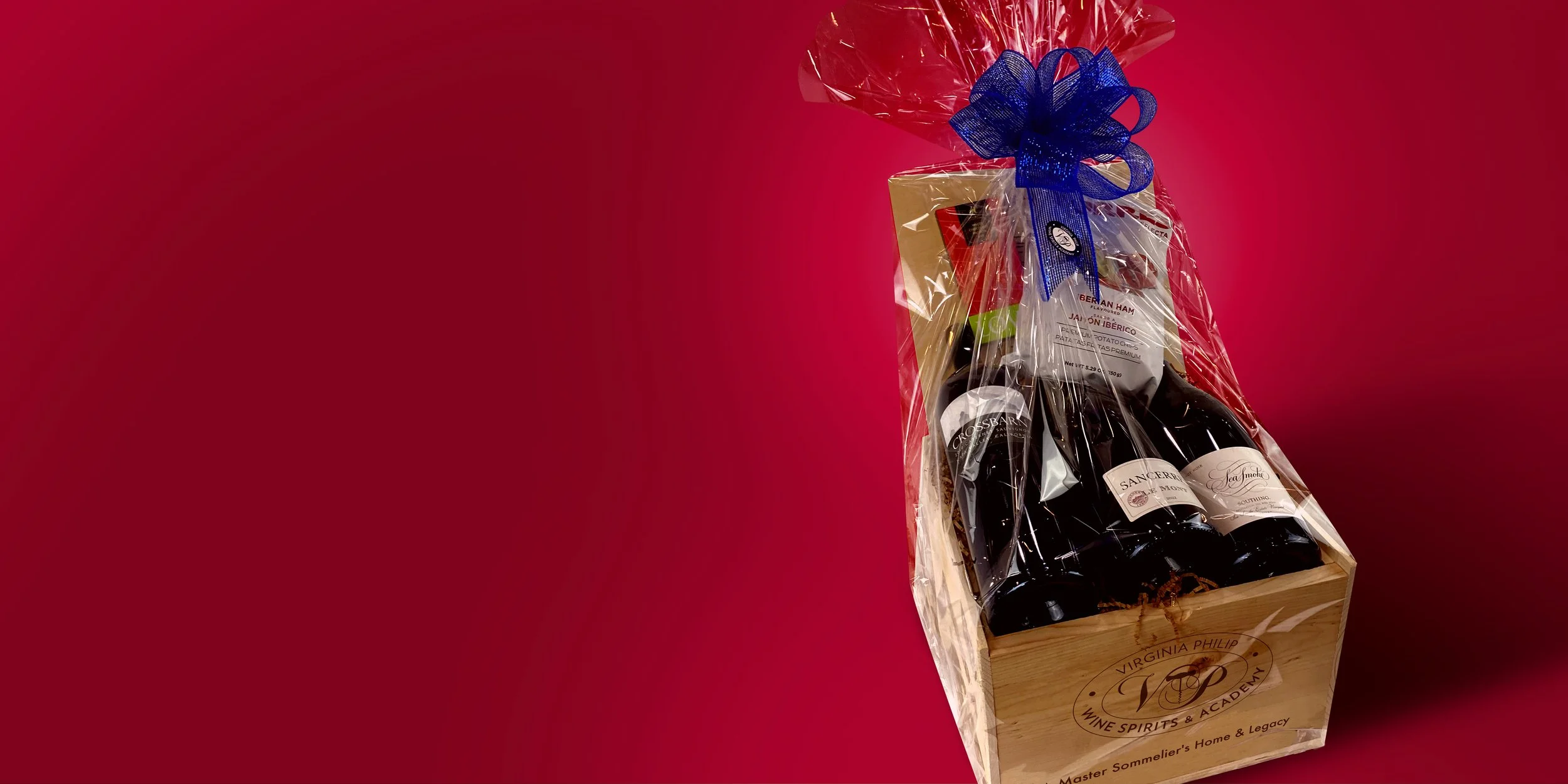 Magnum Triptych wine gift basket featuring three large-format bottles, gourmet snacks, and a blue ribbon, presented in a Virginia Philip branded wooden crate—marketed as “A Big Deal of a Wine Gift” for $685.