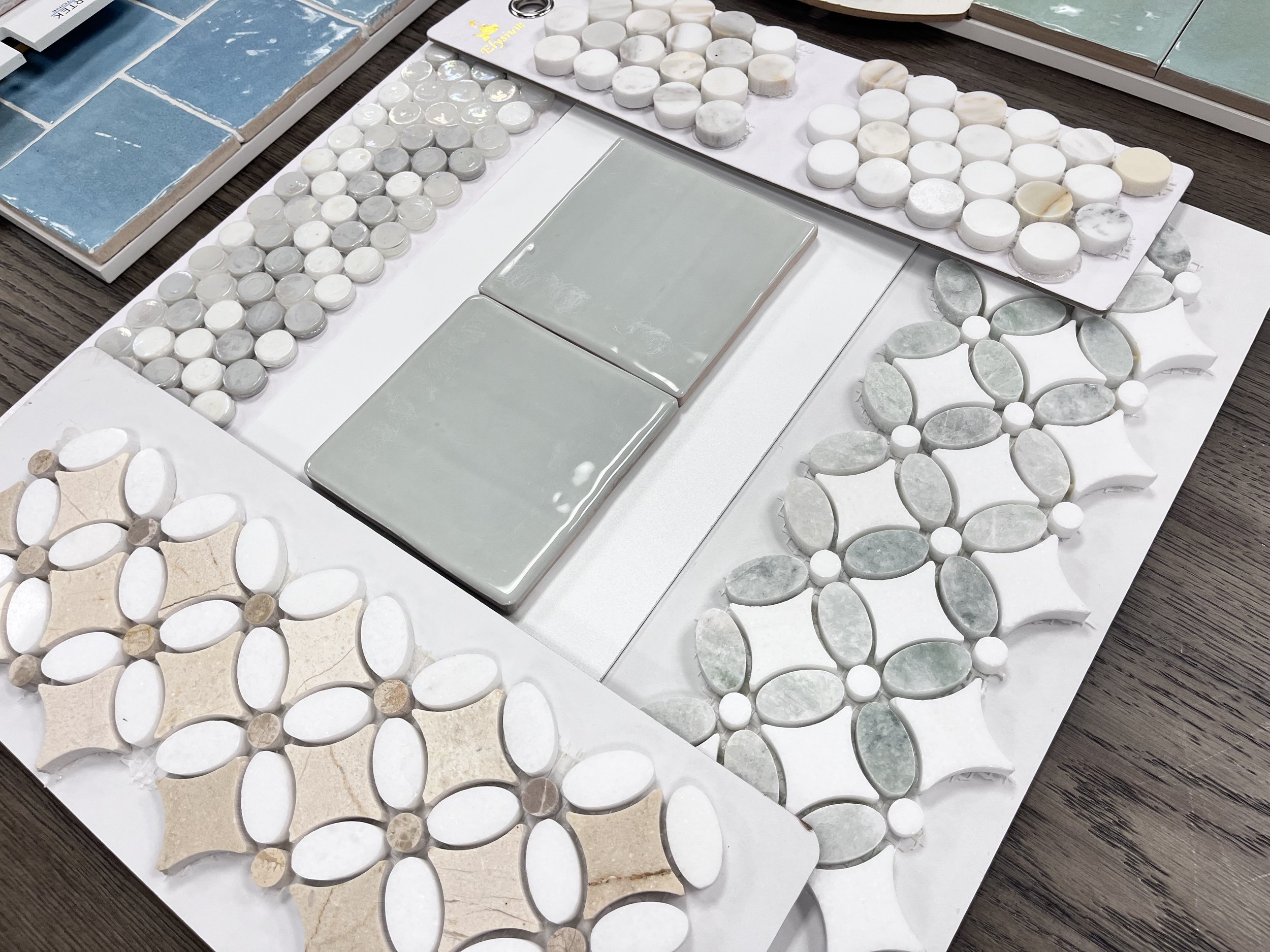 Assorted mosaic tiles with various geometric patterns and colors on display, including round, rectangular, and diamond shapes.