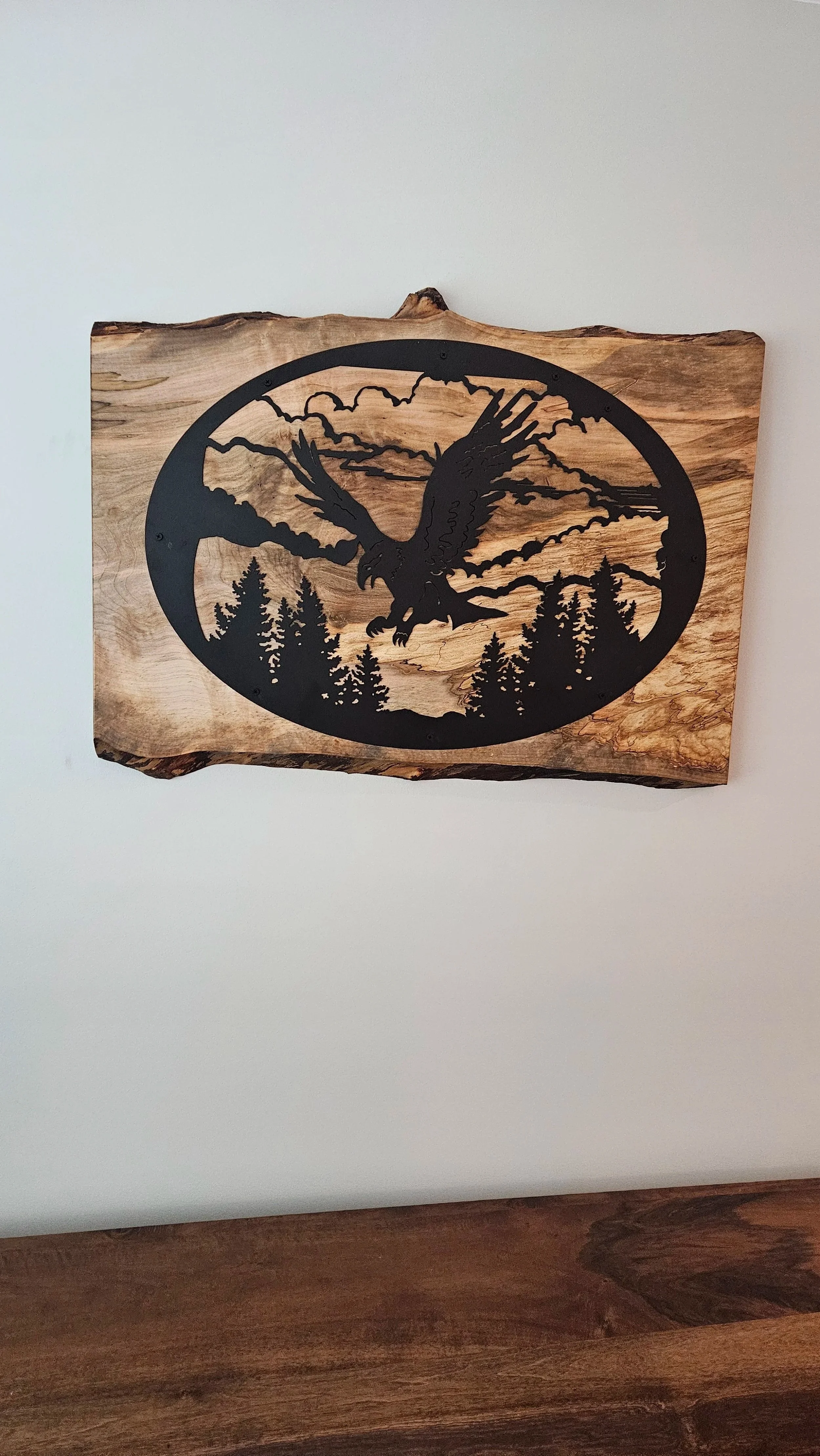 This backing for this sheet metal cut-out is spalted maple, finished with an oil-based wax. A french cleat capable of holding 300 pounds was used to mount it on the wall.