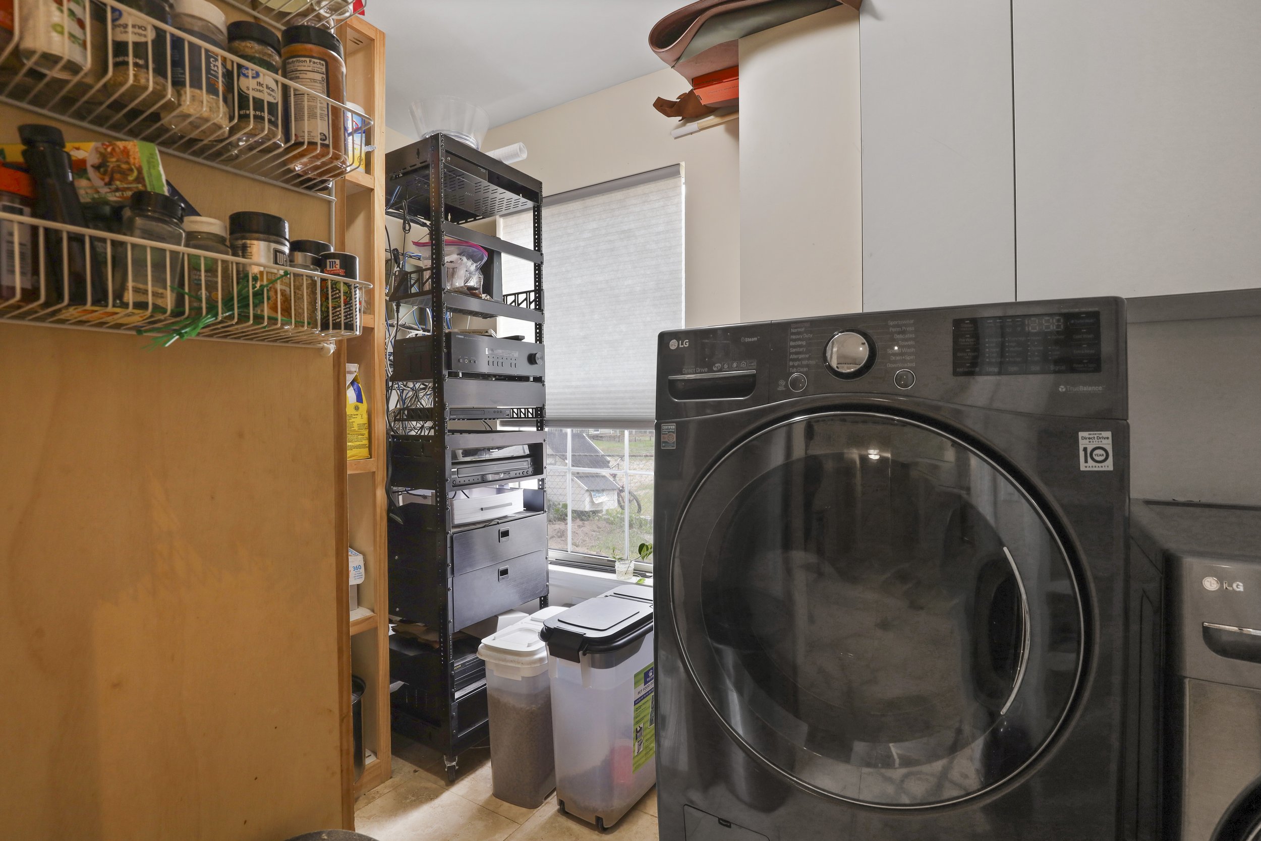 Laundry room with LG washer, storage shelves, and cabinets