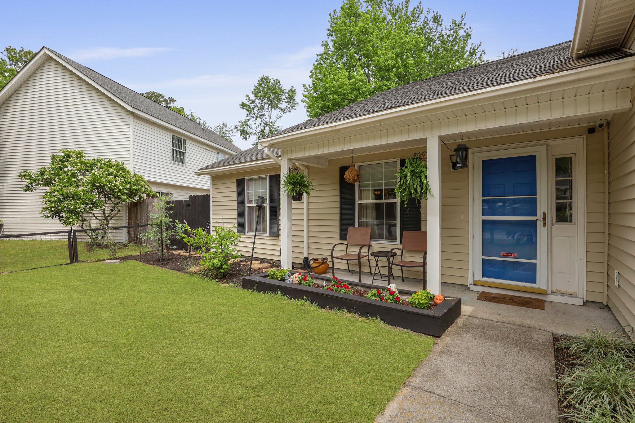 Suburban house with front porch, blue door, potted plants, and lawn