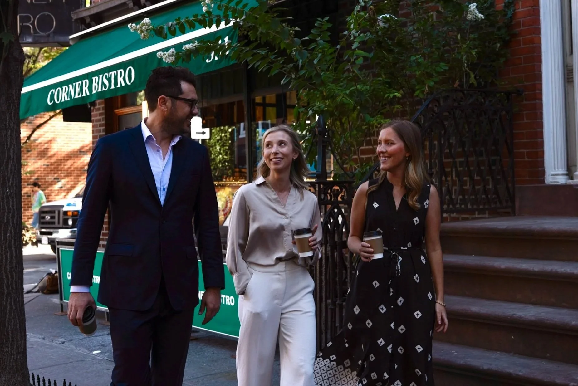 Peltoma Capital Partners advisor team walking on a New York City street. They are holding coffee cups and talking.