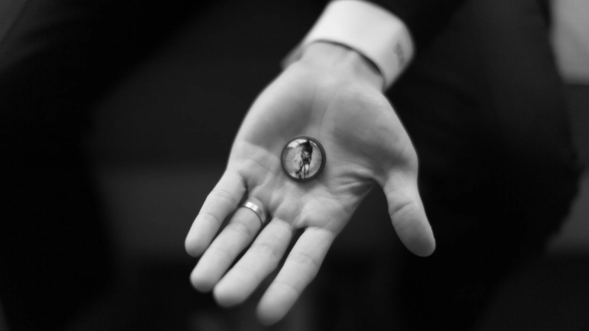 Groom holding a lapel picture pin of his father on wedding day.