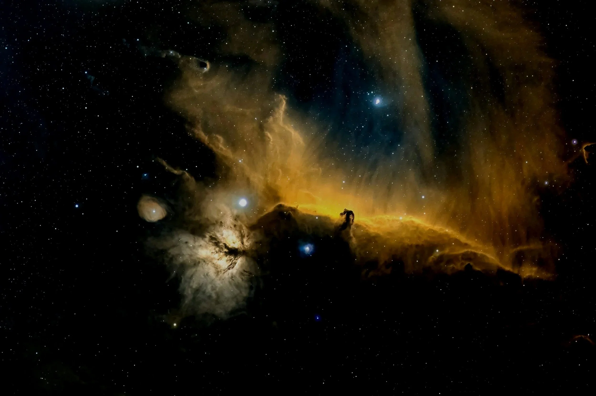 A star-filled deep space nebula with bright gas clouds and dust formations, including the Horsehead Nebula.