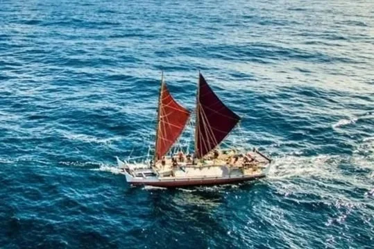 A sailboat with red sails sailing on the ocean