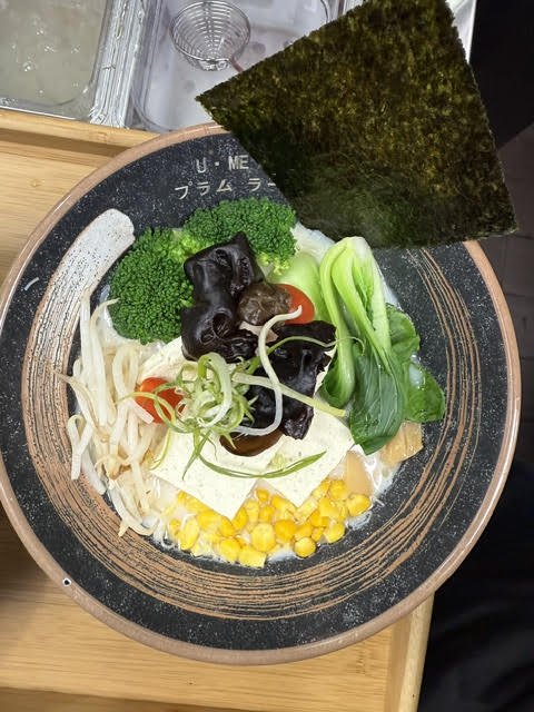 Vegetarian ramen bowl featuring tofu, corn, bok choy, wood ear mushrooms, broccoli, cherry tomatoes, bean sprouts, and nori in a ceramic bowl.