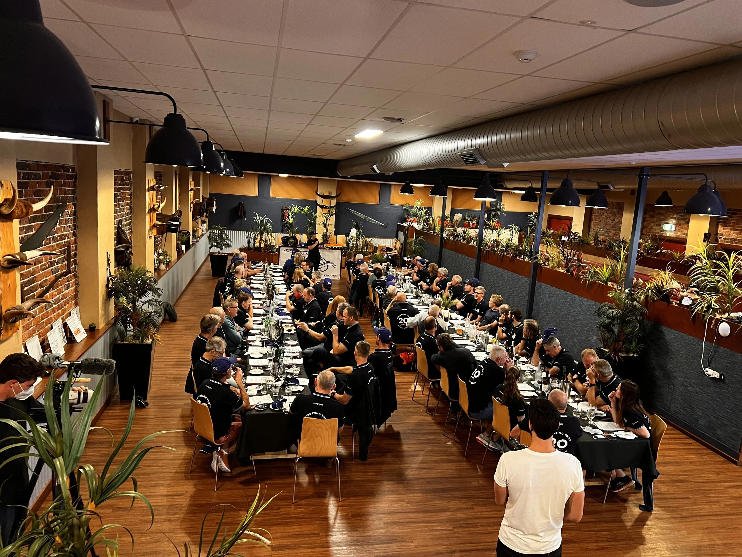 Functions are welcome at Rustlers. A large group of people seated at long tables in a restaurant, engaged in a meeting or event, with some standing at the front.
