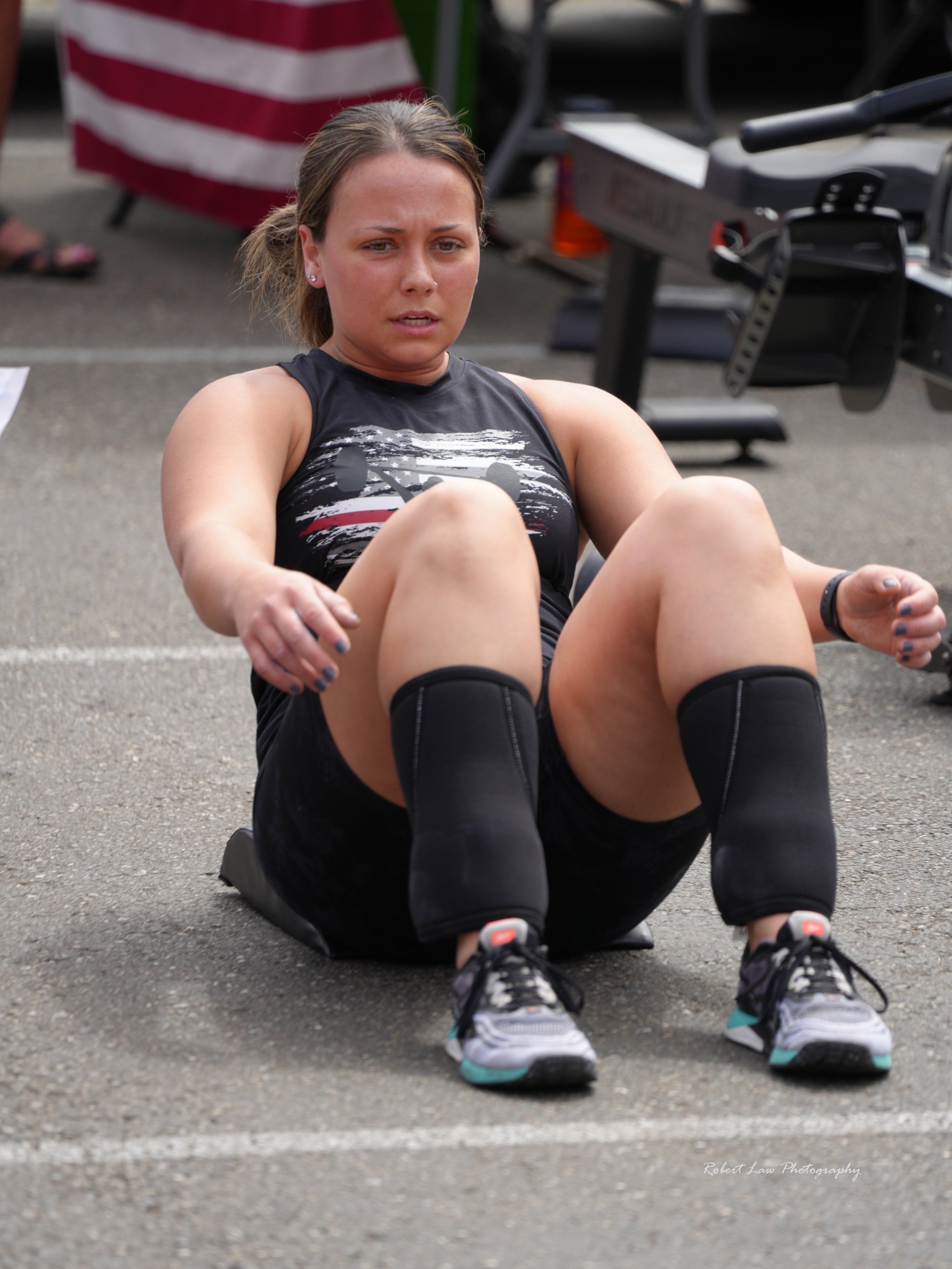 Person doing sit-ups outdoors on a mat, wearing athletic gear, with exercise equipment in the background.