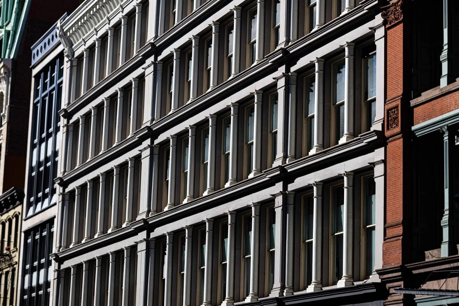 Close-up view of the ornate facade of multiple buildings with decorative columns and large windows in an urban setting