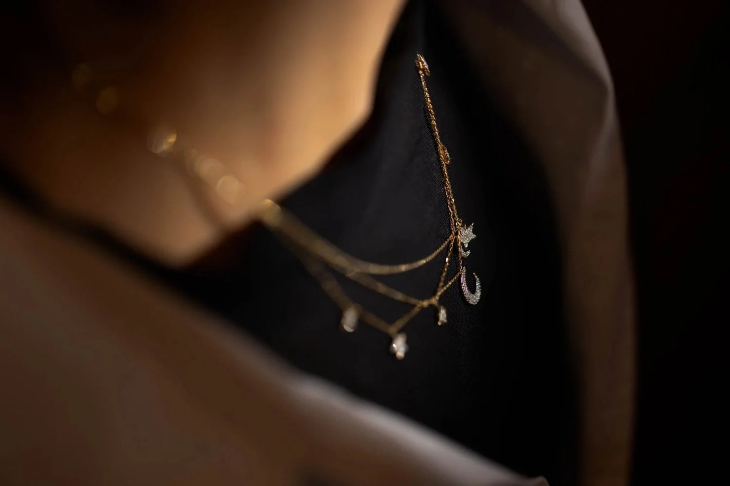 Gold and silver layered necklaces with star, moon, and cross pendants inside a jewelry box.