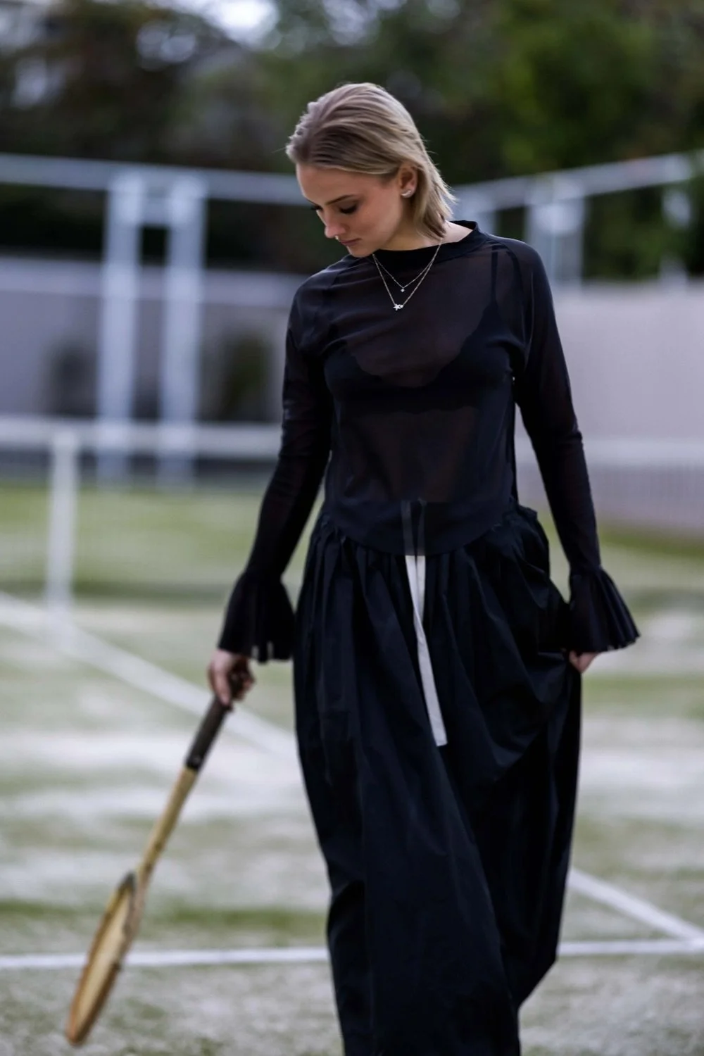 Woman in black outfit holding a tennis racket on a tennis court