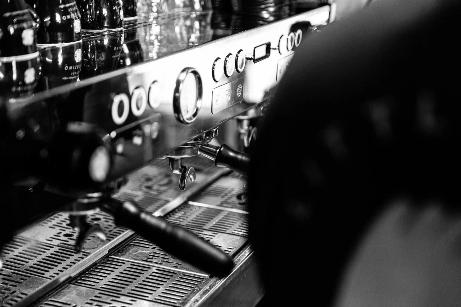Close-up of a professional espresso machine with knobs and handles, black and white photo.