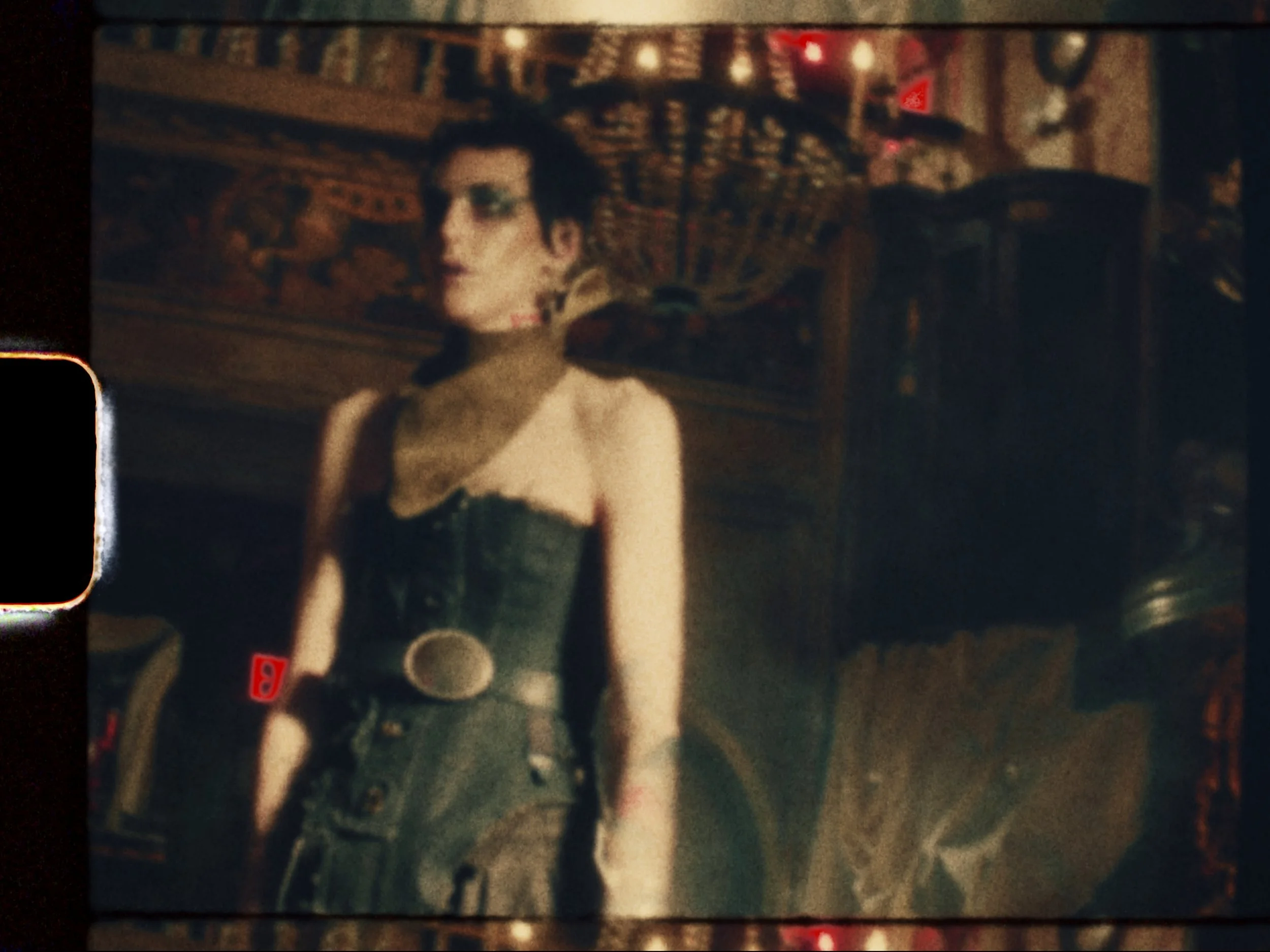 A woman dressed in a black corset with a choker necklace, standing in a dimly lit, vintage-style setting with warm lighting.